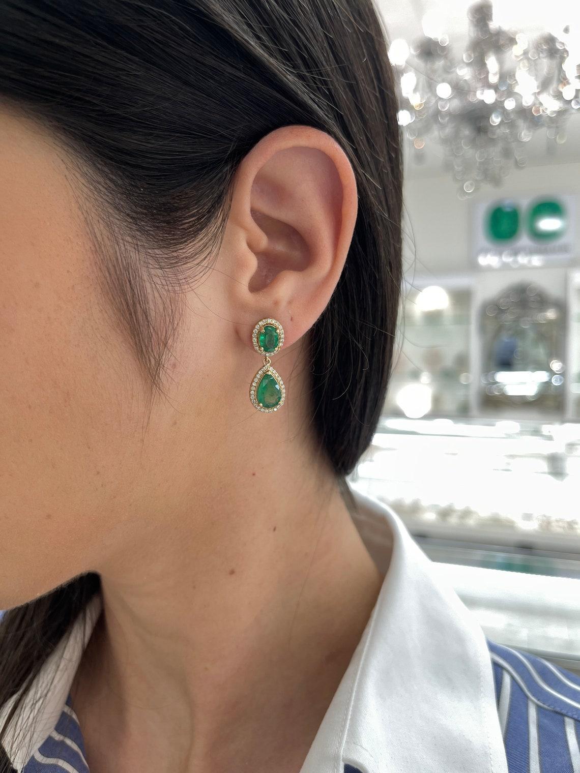 Indulge in the epitome of elegance with our emerald and diamond dangle earrings, featuring a mesmerizing cascade of emeralds and diamonds. Beginning at the earlobe, 2.0 total carats of oval-cut emeralds are delicately prong-set and encircled by a