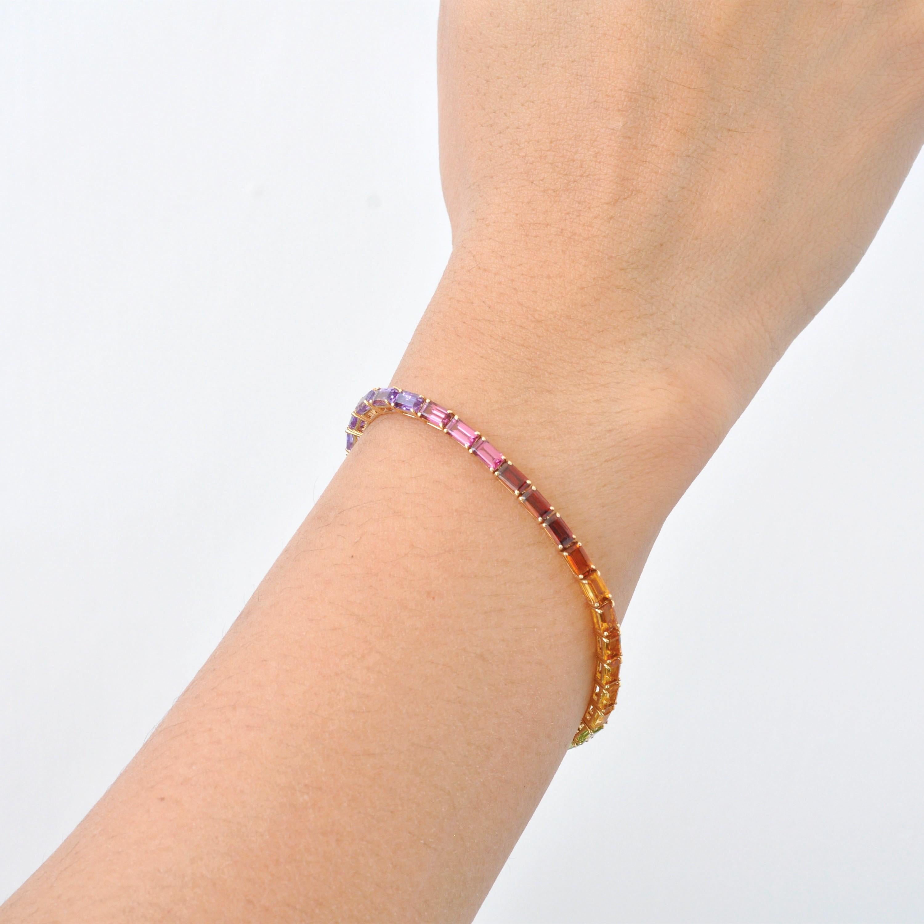 Questo braccialetto con linea tennis con gemme arcobaleno in oro bianco 14K è una celebrazione radiosa del colore, dell'eleganza e della maestria artigianale. Caratterizzato da una fila continua di gemme dal taglio ottagonale di 5x3 mm, questo pezzo