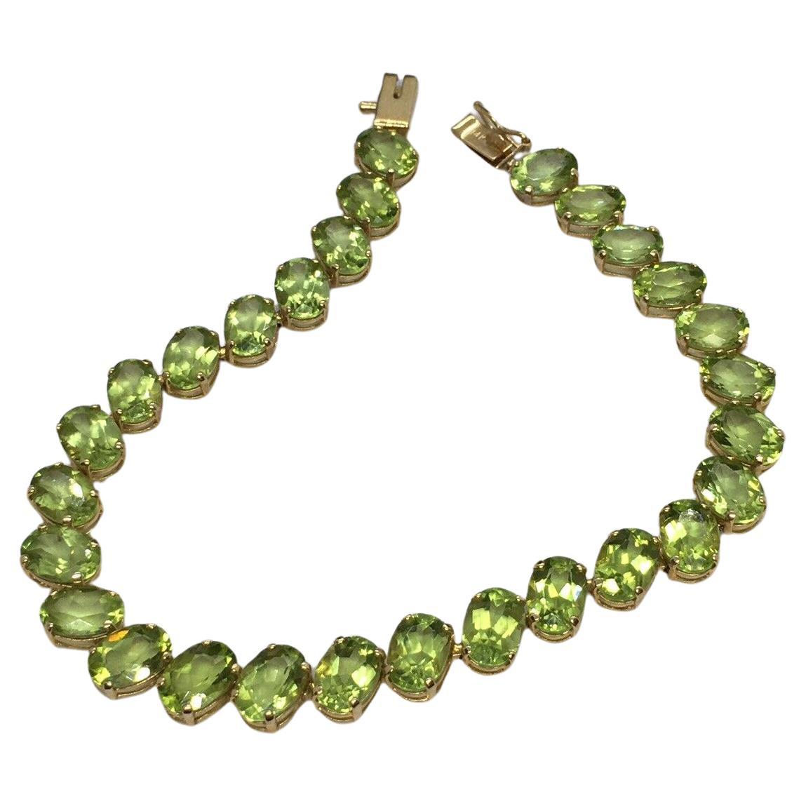 14K gold 7 mm by 5 mm 28 Oval Natural Peridot Tennis Bracelet Women 7.25 inch For Sale
