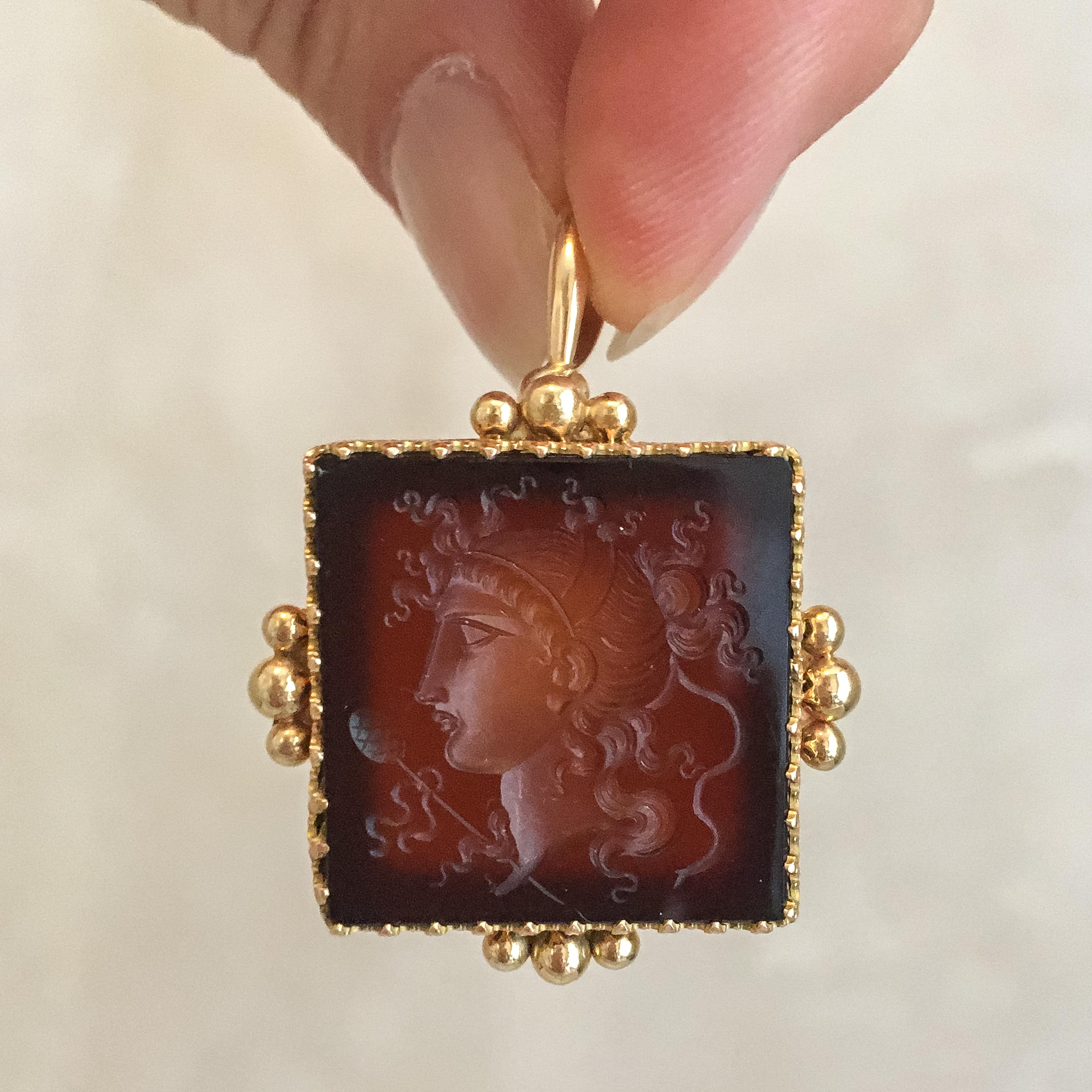 A neo-classical agate intaglio pendant created in a 14 karat gold frame. The square-shaped intaglio features a neo-classical woman in profile set in a gold frame with beading on each side. The intaglio is clearly a work of a great gem carver. The