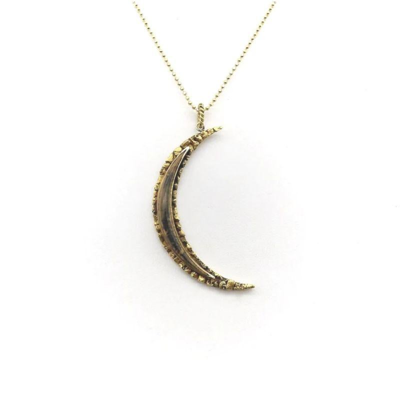 This crescent moon pendant is from the Alaskan Gold Rush era. The moon is a thin sliver, either a waxing or waning crescent in its moon cycle. On the front of the pendant are pieces of 22k Alaskan gold, which have been carefully soldered on top of a