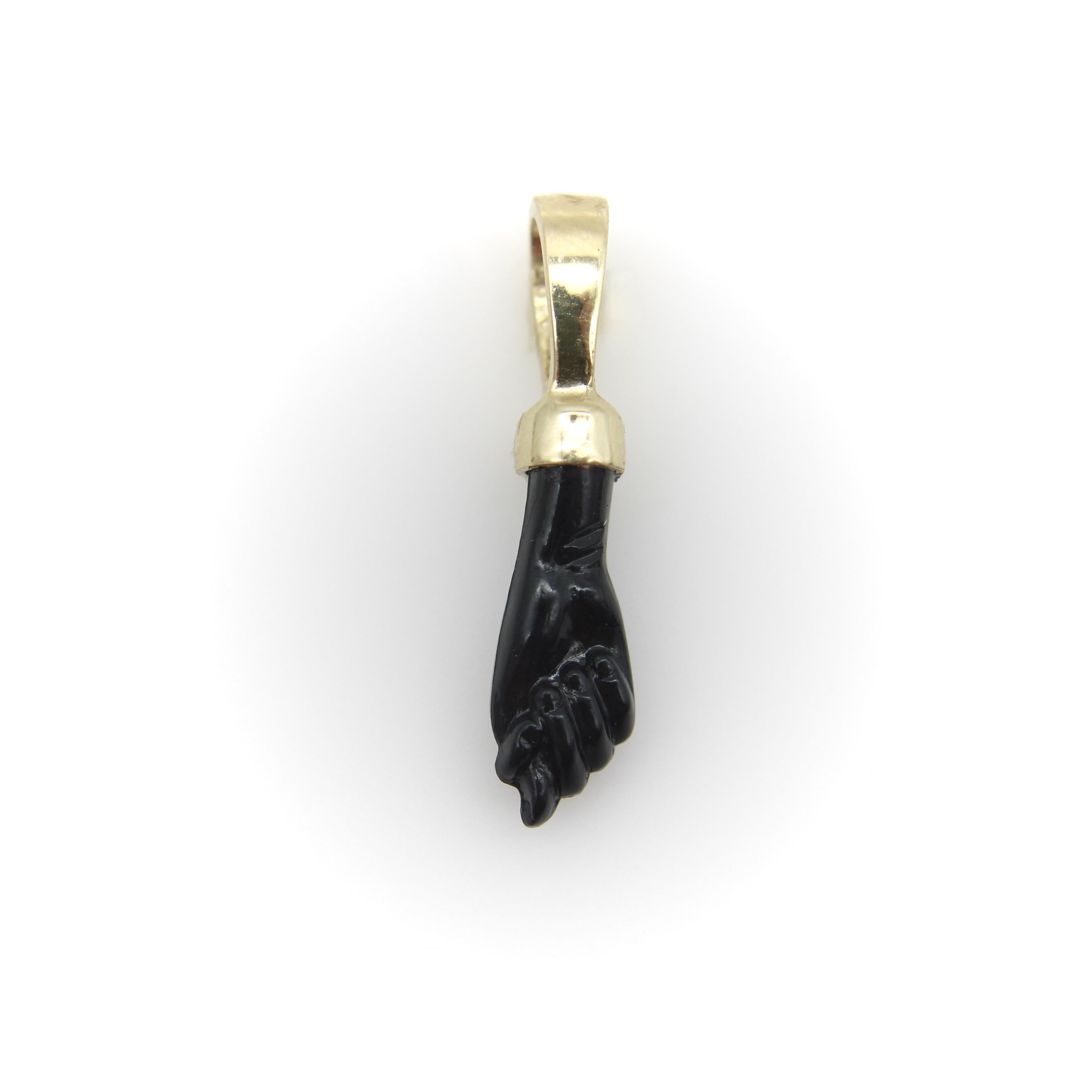This 14k gold and glass pendant is the traditional Figa symbol, known in many cultures as a good luck charm and protective talisman against the Evil Eye. 
The clenched fist with a thumb extended between two fingers represents femininity and dates