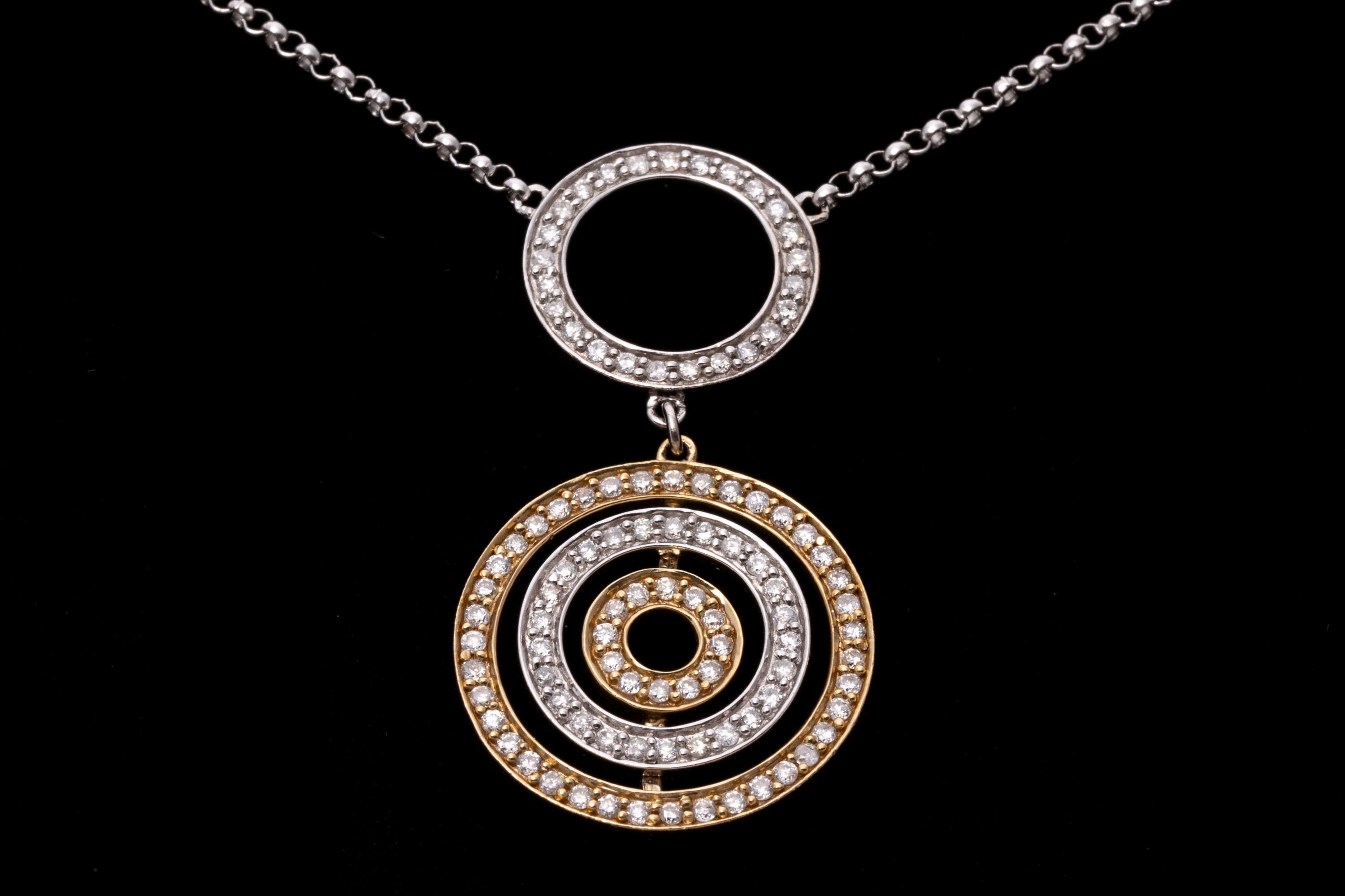 14k white and yellow gold necklace. This fun, contemporary necklace contains a curb link chain featuring two small open circle stations, set with round faceted diamonds, prong set. In the center is a larger open circle, with an articulated drop