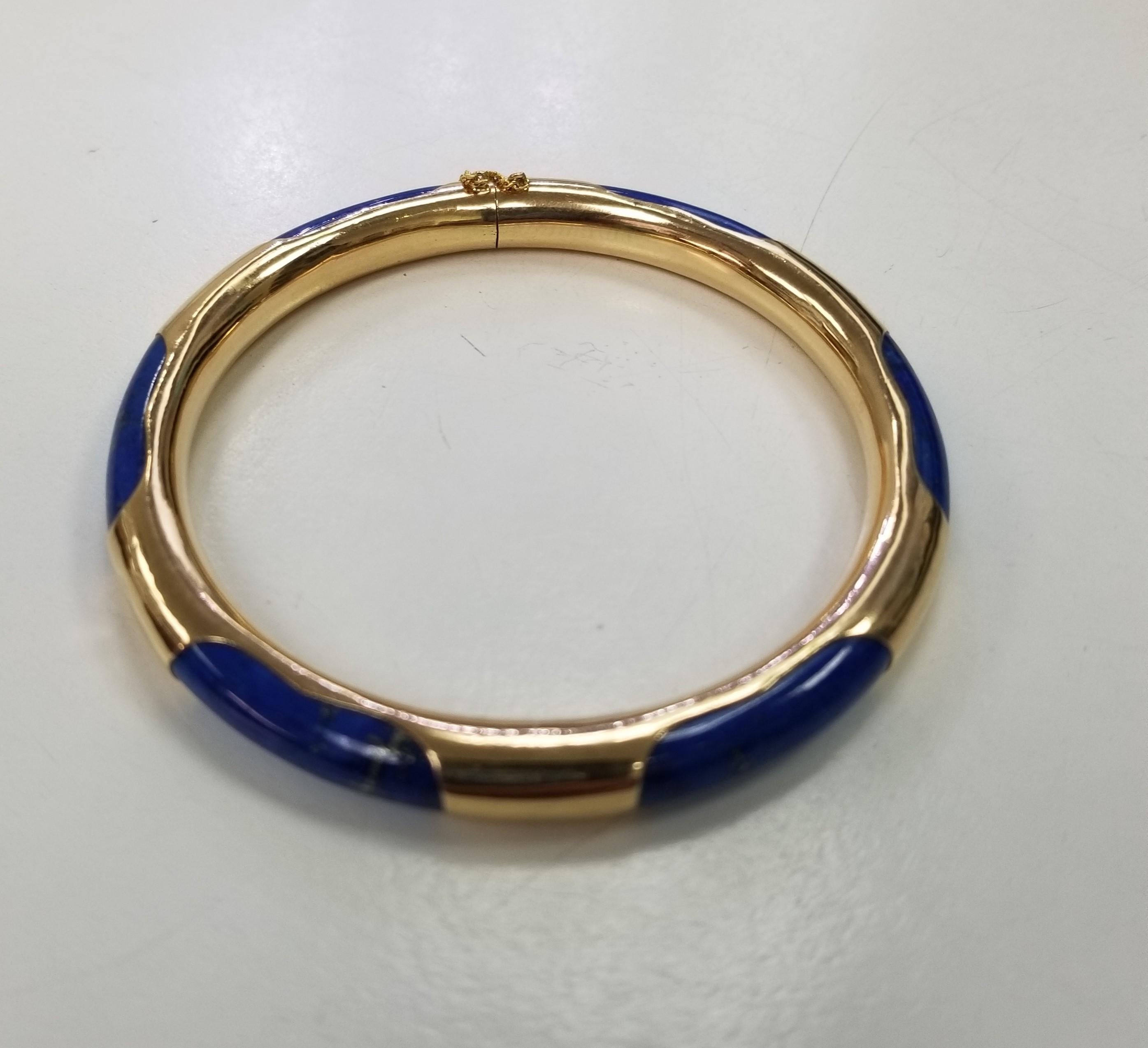 14k yellow gold and Lapis Lazuli stone bangle bracelet. Measures 2 1/4 inches inside diameter and 2 3/4 inches outside and 7.25mm wide. Weighs 21 grams. Stamped 14k, maker unknown. with safety chain.


