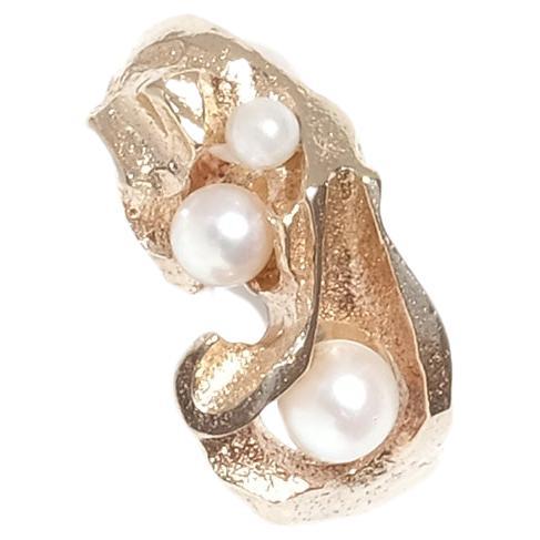 This 14-karat gold ring features a unique, organic-shaped setting that resembles intertwining branches. The setting securely holds four cultured pearls, each positioned at different points within the intricate design. The gold has both a patterned