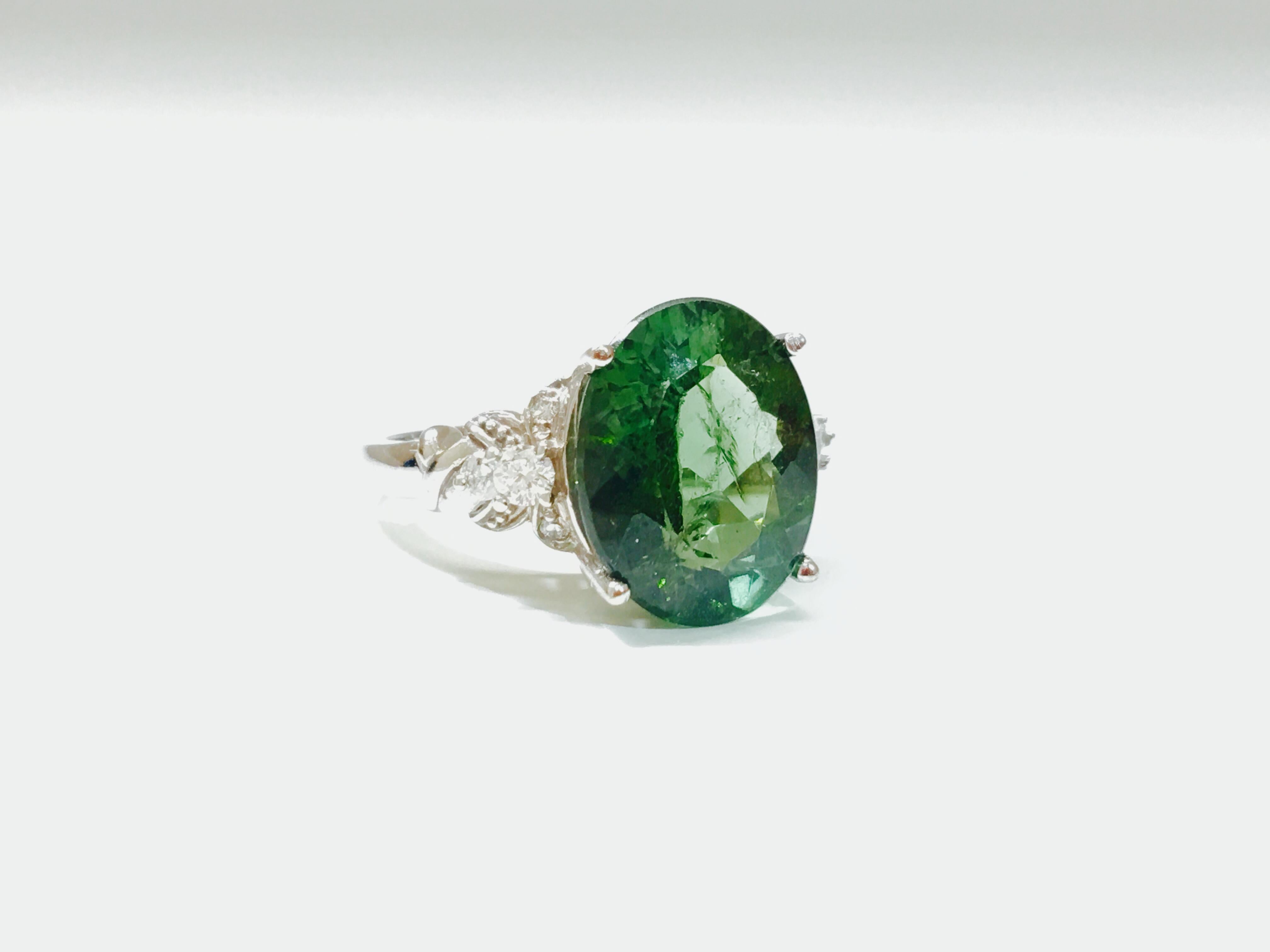 Behold this exquisite ladies gemstone and diamond ring, meticulously fashioned from opulent 14K white gold. The focal point features a mesmerizing oval-shaped andalusite, delicately cradled in prongs, showcasing its natural earth-mined allure.