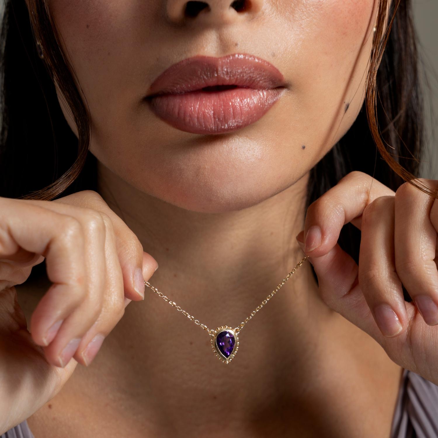 This elegant pendant is set with a pear cut amethyst in solid 14k yellow gold and features granulated spheres around the outside of the rub-over setting. Inspired by creatures of the coral reef, our colourful Anemone collection is fascinating in its