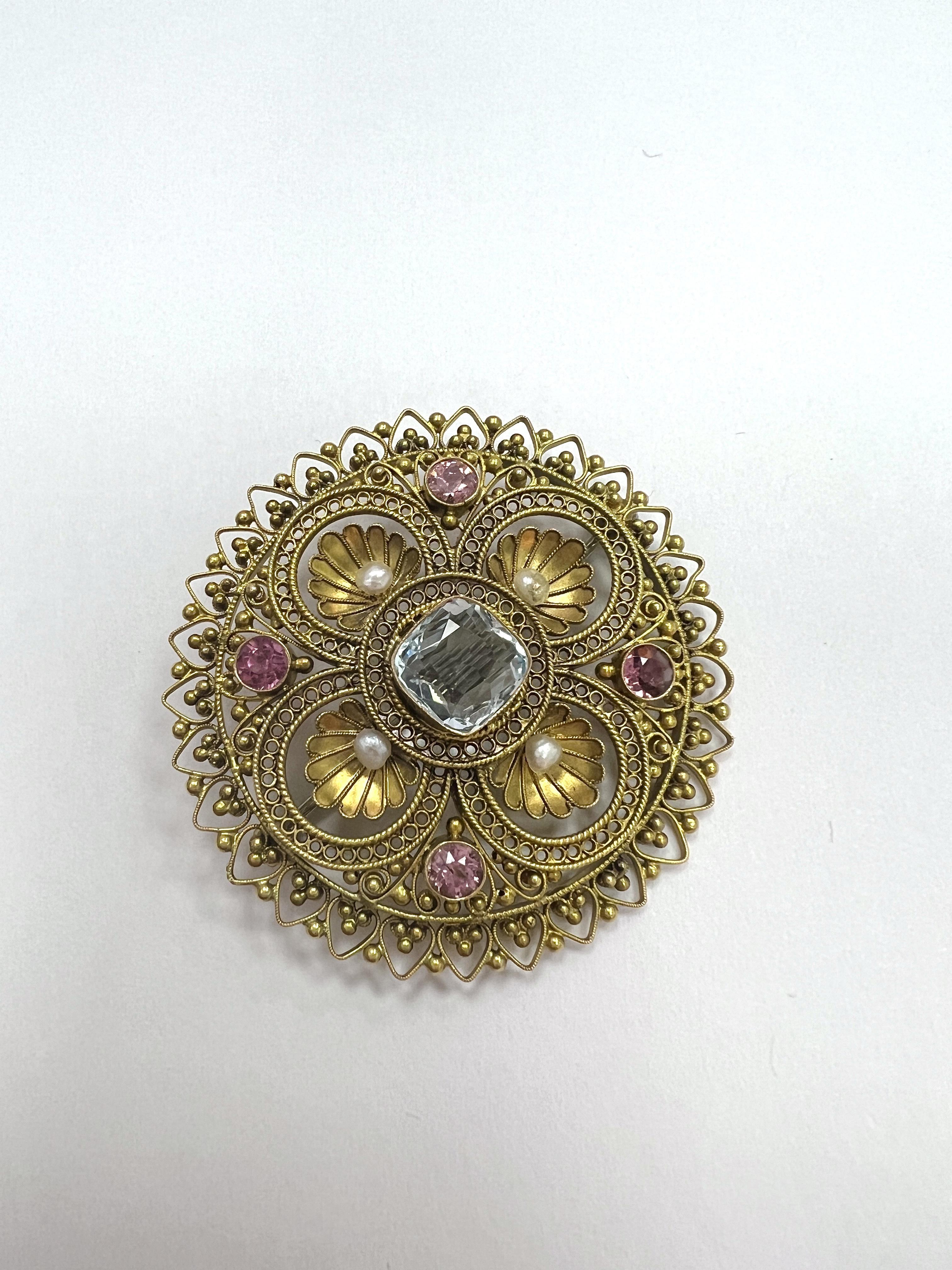 14K Gold, Aquamarine, Tourmaline, And Seed Pearl Brooch.

The circle-form brooch centering a cushion-cut aquamarine measuring approx. 7.51 x 7.41 x 3.47 mm. framed by four seed pearls and four circle-cut pink tourmalines within an engraved and