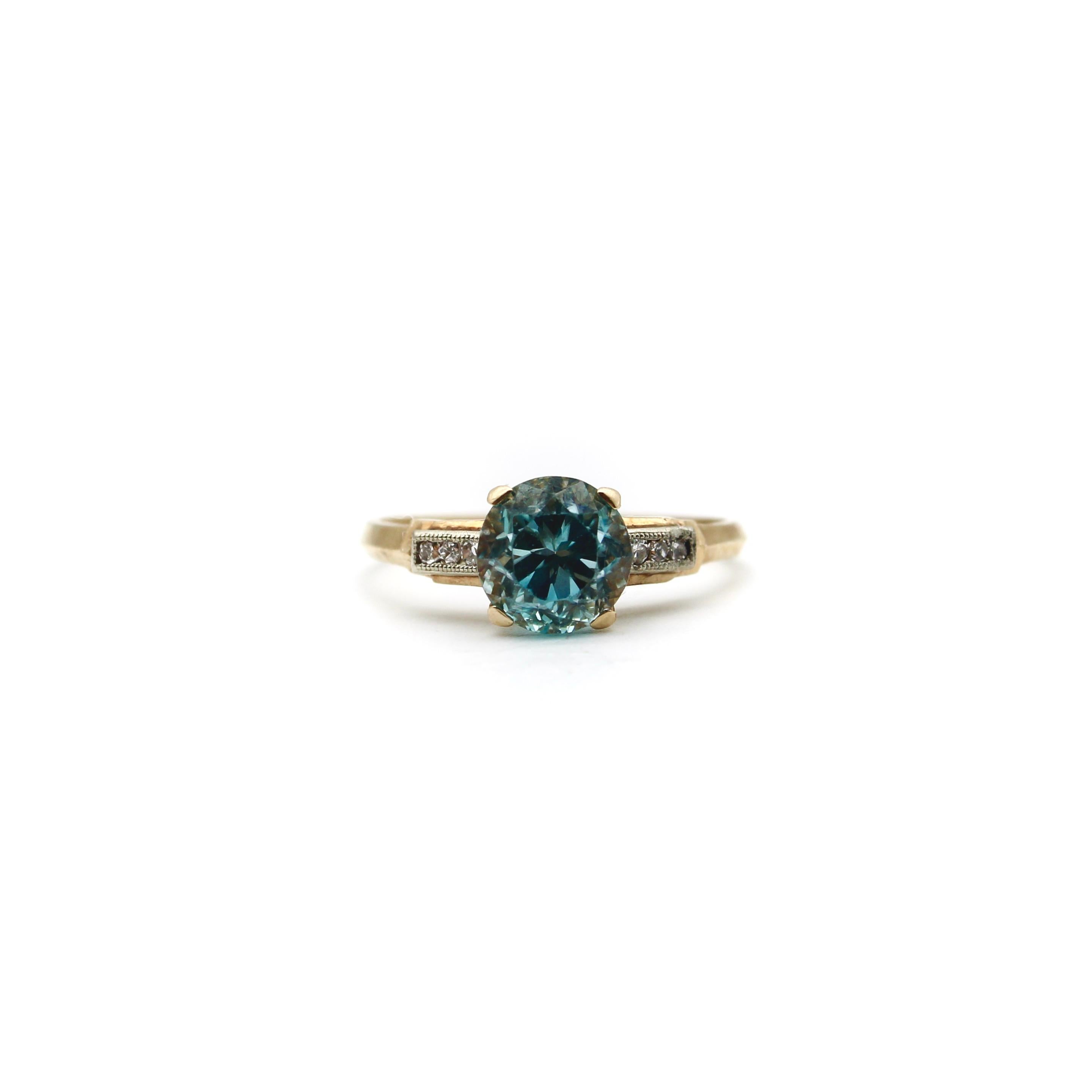 Circa the 1920’s, this 14k gold ring features a Mediterranean blue zircon, set between rows of single cut diamonds. The zircon is an Old European Cut, with high facets that are very reflective of the light and have a mesmerizing shimmer. Zircon is