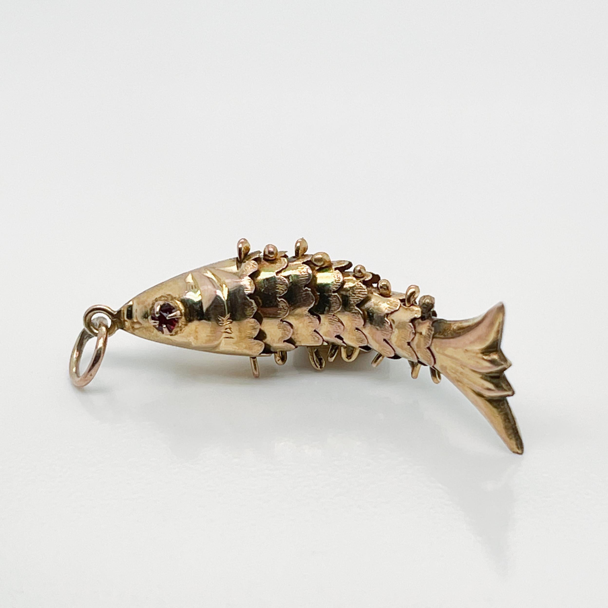 A very fine 14 karat gold articulated fish charm.

Set with garnet gemstone eyes.

Simply a wonderful charm!

Date:
20th Century

Overall Condition:
It is in overall good, as-pictured, used estate condition with some very fine & light surface