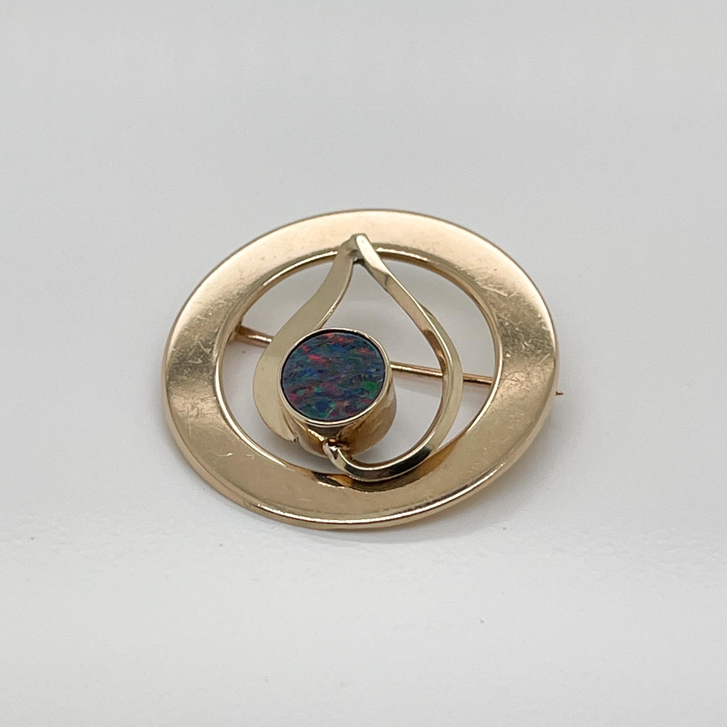 A very fine 14k gold and Australian opal doublet brooch or pin.

With a round doublet opal bezel set in 14k gold inside inverted heart shape that is framed in a flat golden circle.  

Simply a terrific brooch!

Date:
20th Century

Overall