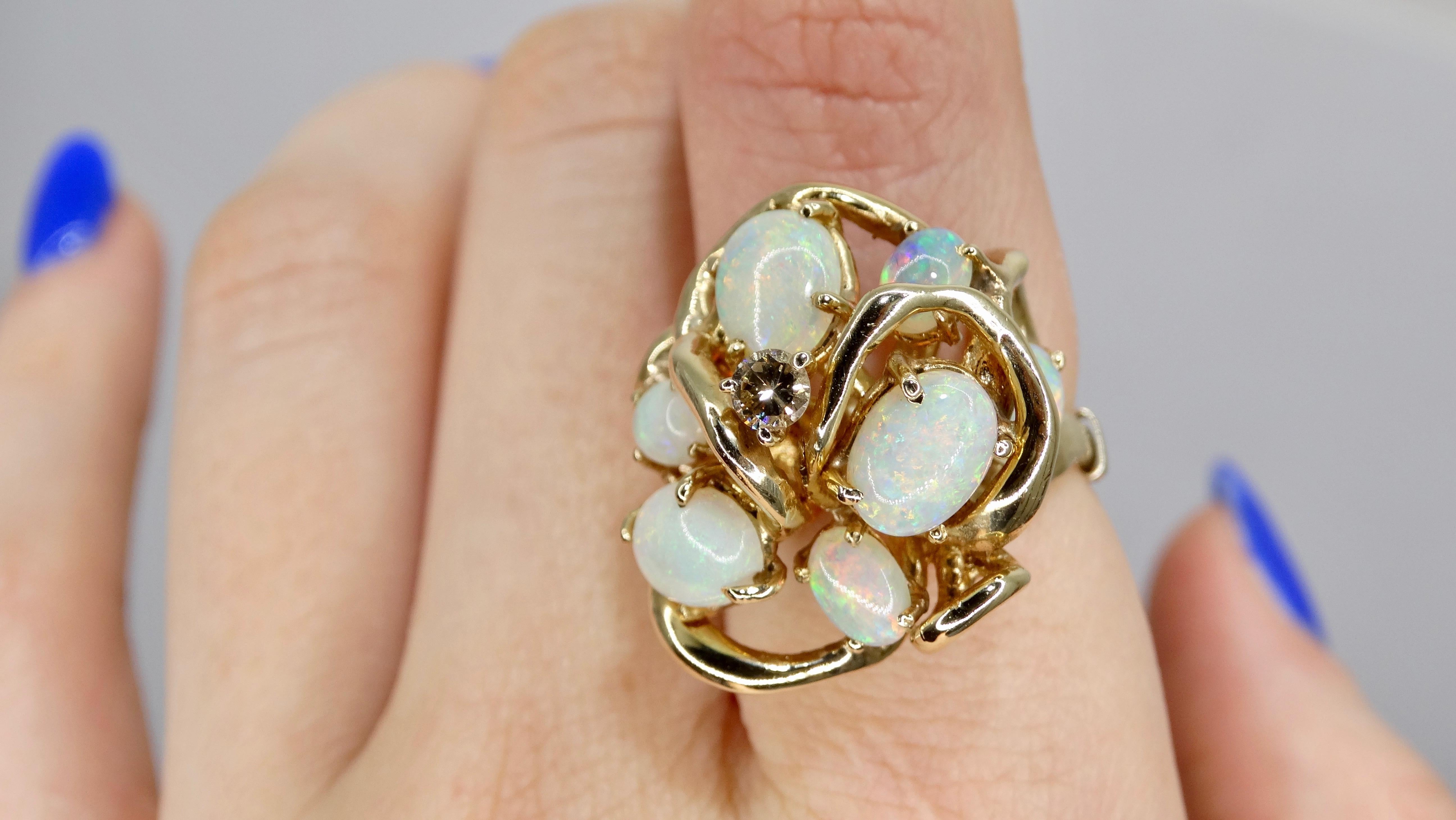 ¡Una pieza atemporal para cualquier colección de joyas! Este anillo de cóctel, de mediados del siglo XX, tiene una banda de oro de 14 quilates. En el engaste nido entrelazado descansa un racimo de Ópalos Australianos con un centro de Diamante. El
