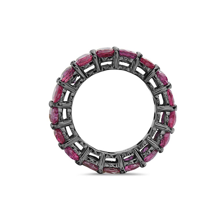This eternity band ring features 17 oval cut rubies weighing 7.35 carats set in 6.1 grams of 14k gold dipped in black rhodium. Size 6. 