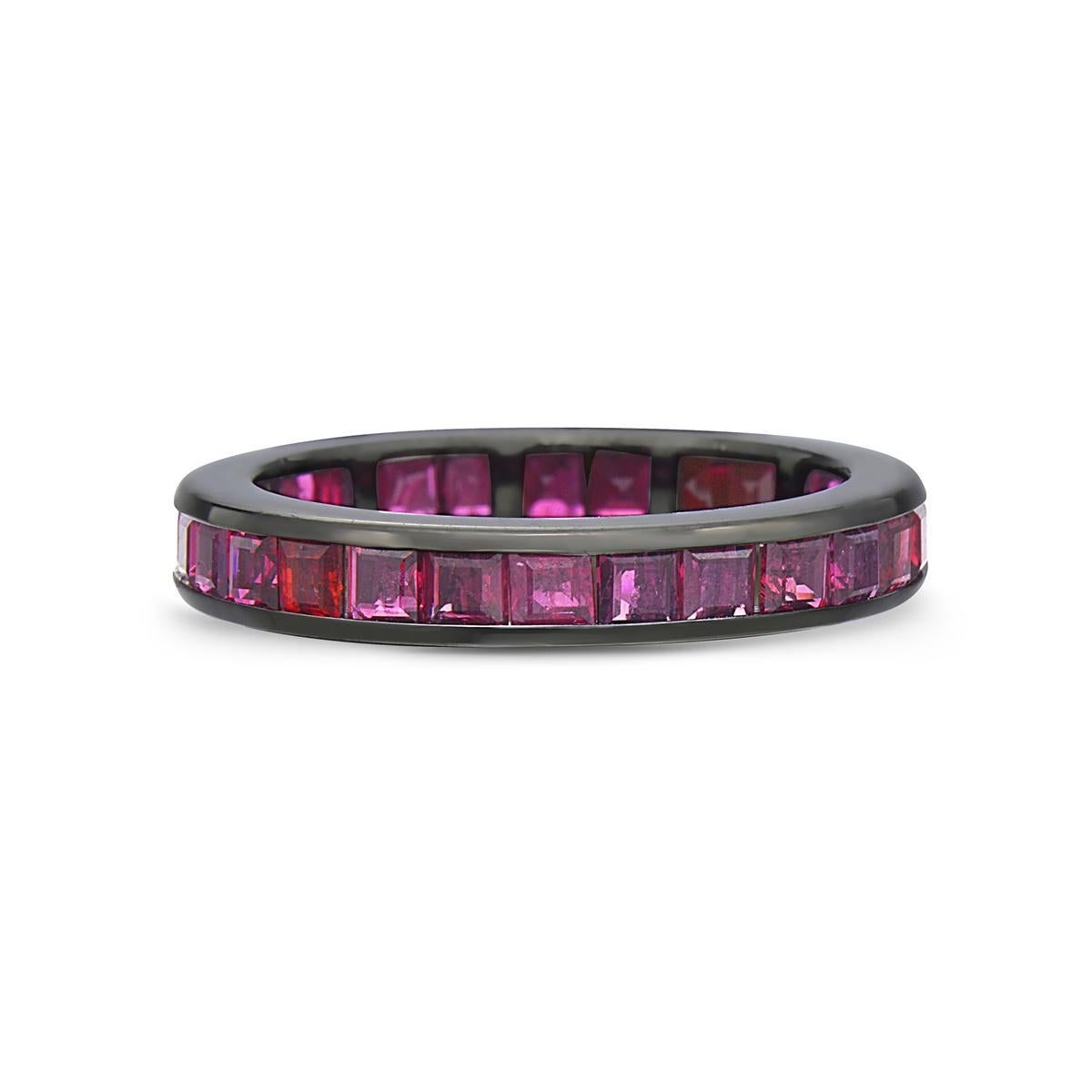 This slim eternity band ring features 28 square cut baguette rubies weighing 2.55 carats set in 14K gold dipped in rhodium. 6.1 grams total weight. Size 6.