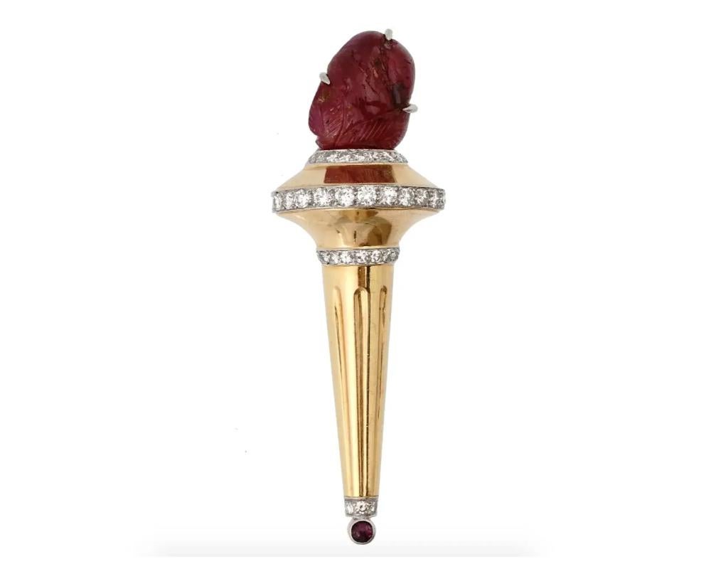 A retro 14K Gold figural brooch. The brooch is made in a shape of a torch, engraved with detailed patterns. The ware is adorned with hand carved 13cts Ruby stone and 85 cts Diamonds. Marked with a standard Gold hallmark, and impressed number. Weight
