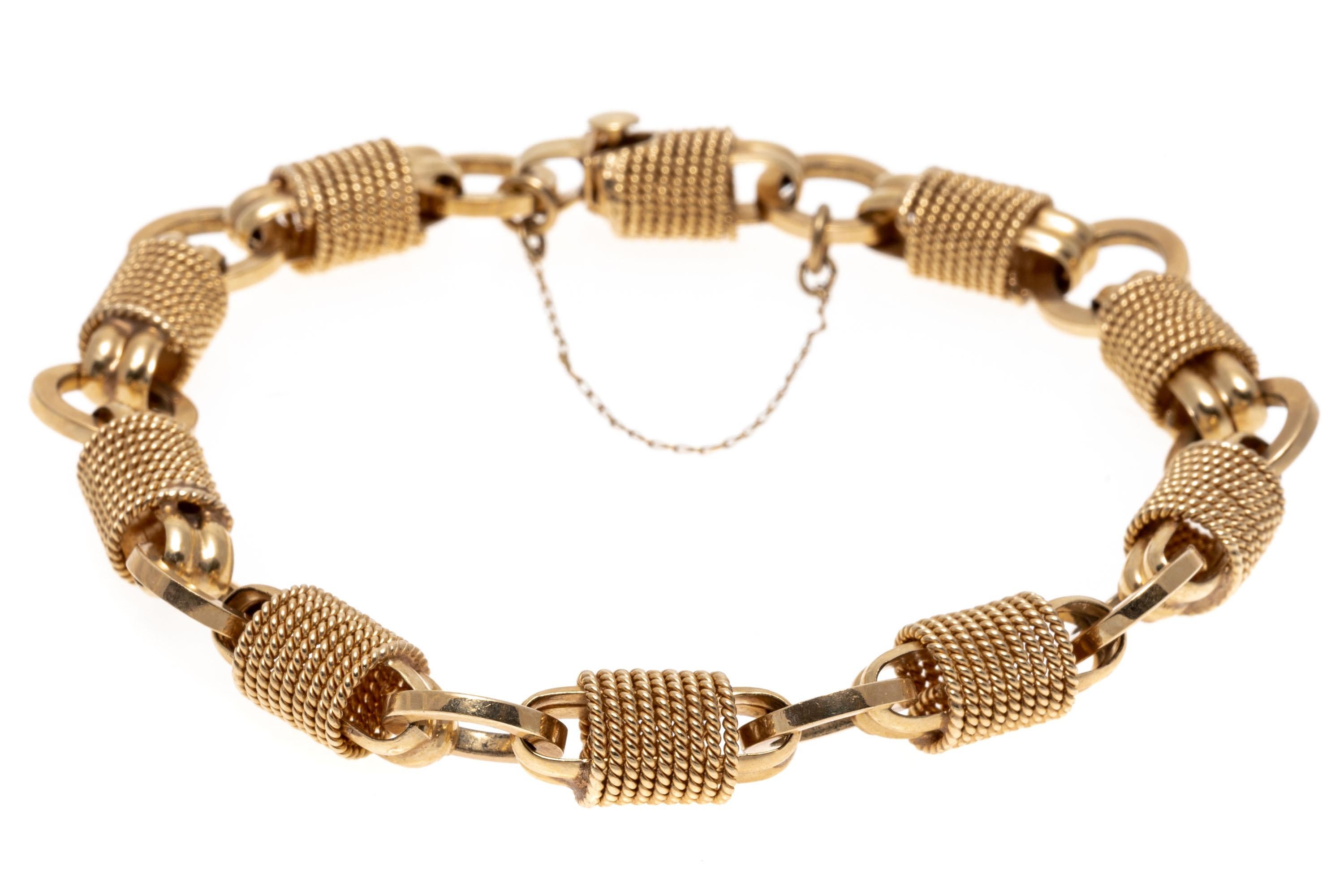 This unique 14K yellow gold bracelet presents alternating round and barrel styles links. The barrel links are wrapped in a twisted rope display, adding a rustic appeal. Box style clasp with safety latch and chain for added security.
Marks: 14K