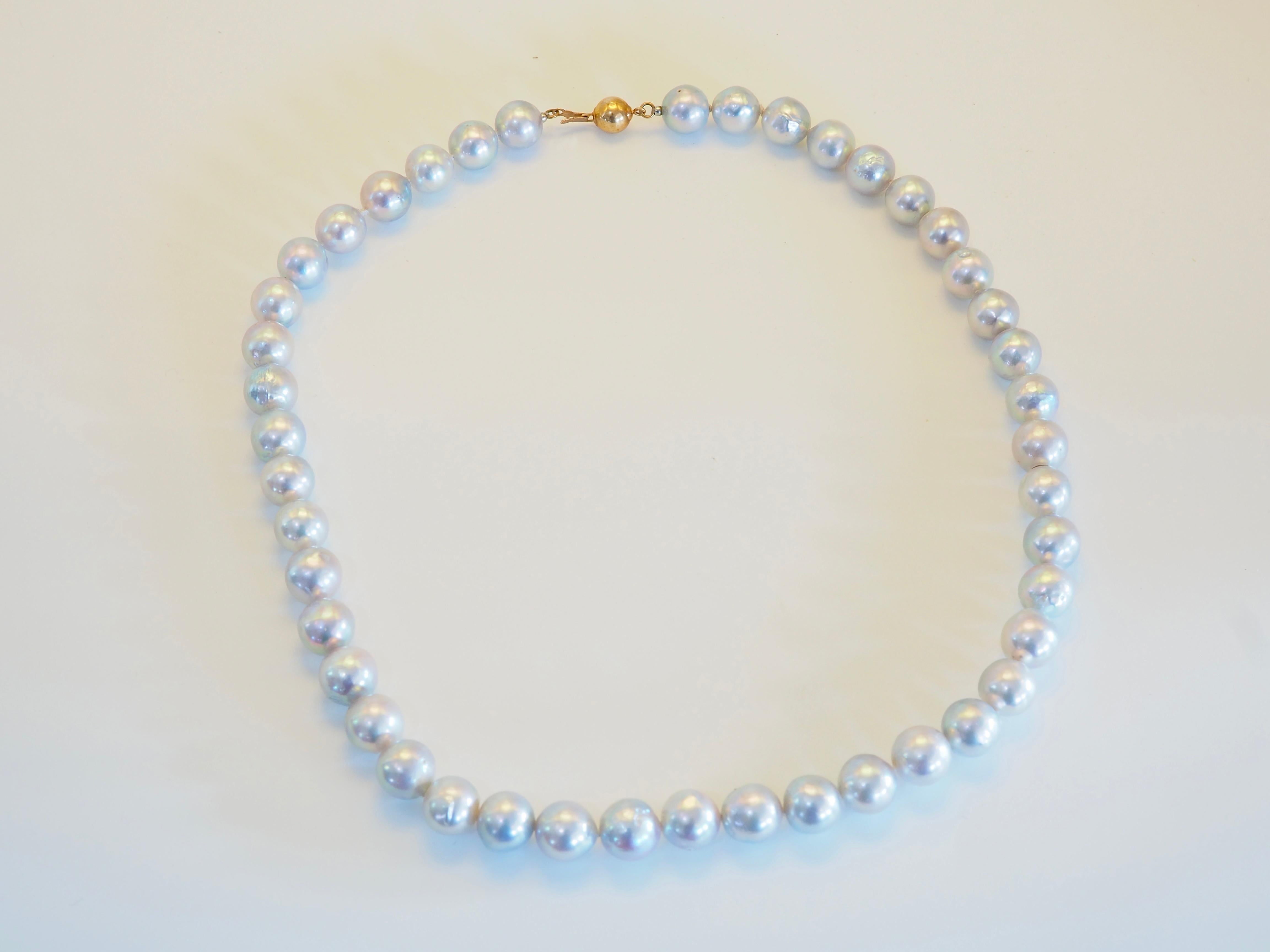 Un luminoso collar de perlas de mar grises metalizadas, cada una de 9 mm de diámetro de media, dispuestas con gracia para formar una silueta clásica de 17 pulgadas. Las perlas exhiben una suave iridiscencia con sutiles matices plateados y grafito,