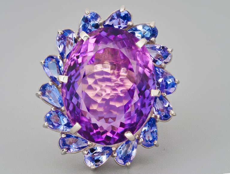 14 kt solid massive flower ring with natural amethyst, tanzanites and diamonds. February birthstone. December birthstone.
Weight approx. 10 g.

Central gemstone: Natural amethyst
Weight: approx 15.00 ct, oval cut, color violet
Clarity: Transparent
