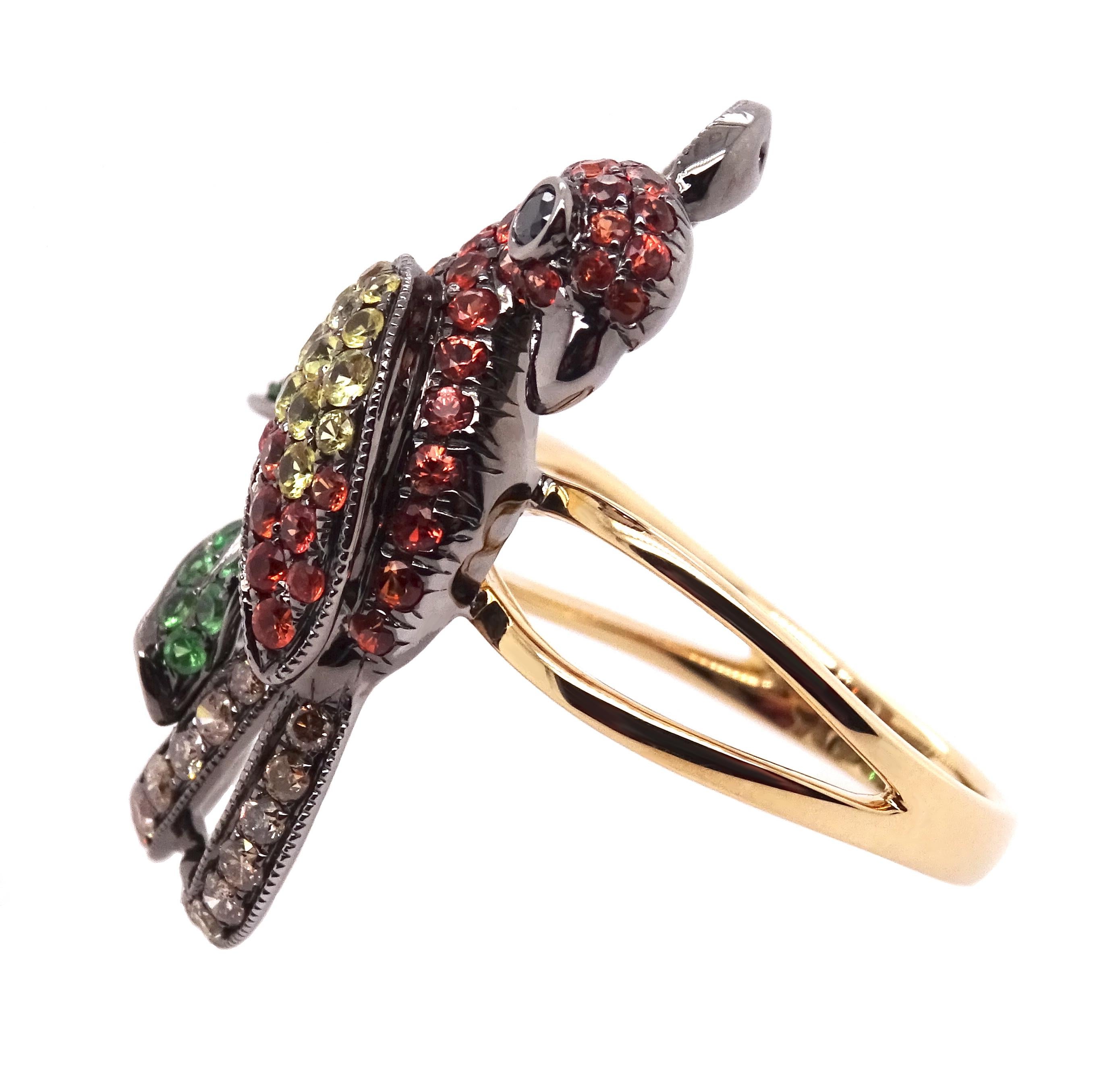 Behold this ravishing parrot ring, a dazzling piece that brings out the inner jungle adventurer in you! Crafted with love from 14K yellow gold, this playful parrot design is adorned with a vibrant plumage of diamonds, garnets, and sapphires,