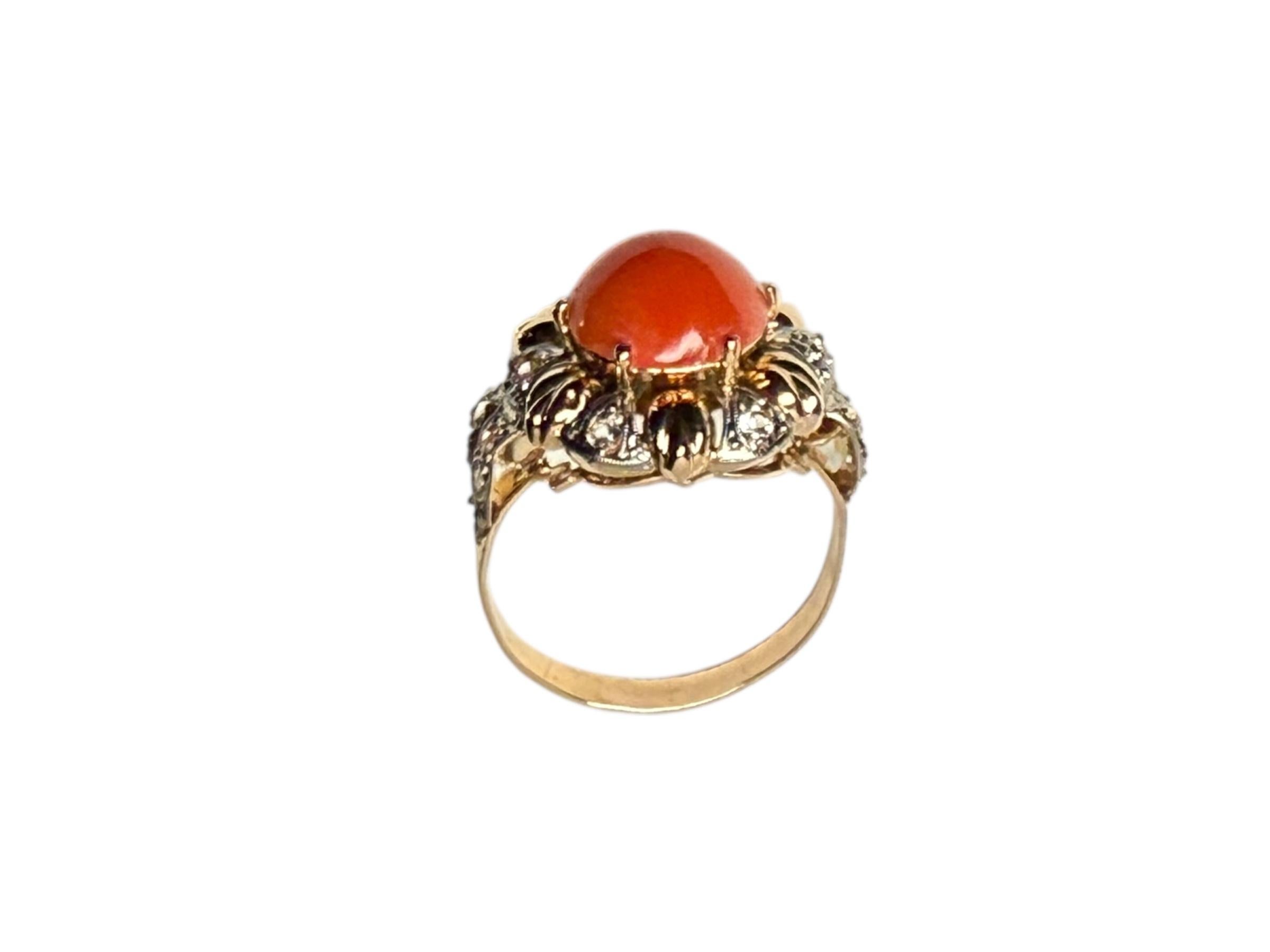 Dies ist ein 14K Gold Coral Sapphire Ring. Es zeigt einen blumenförmigen Ring, der in der Mitte mit einem runden Korallen-Cabochon von 10,7 mm geschmückt ist. Einige weiße Saphire im Brillantschliff mit einer Größe von 2 mm veredeln den Ring. Sein