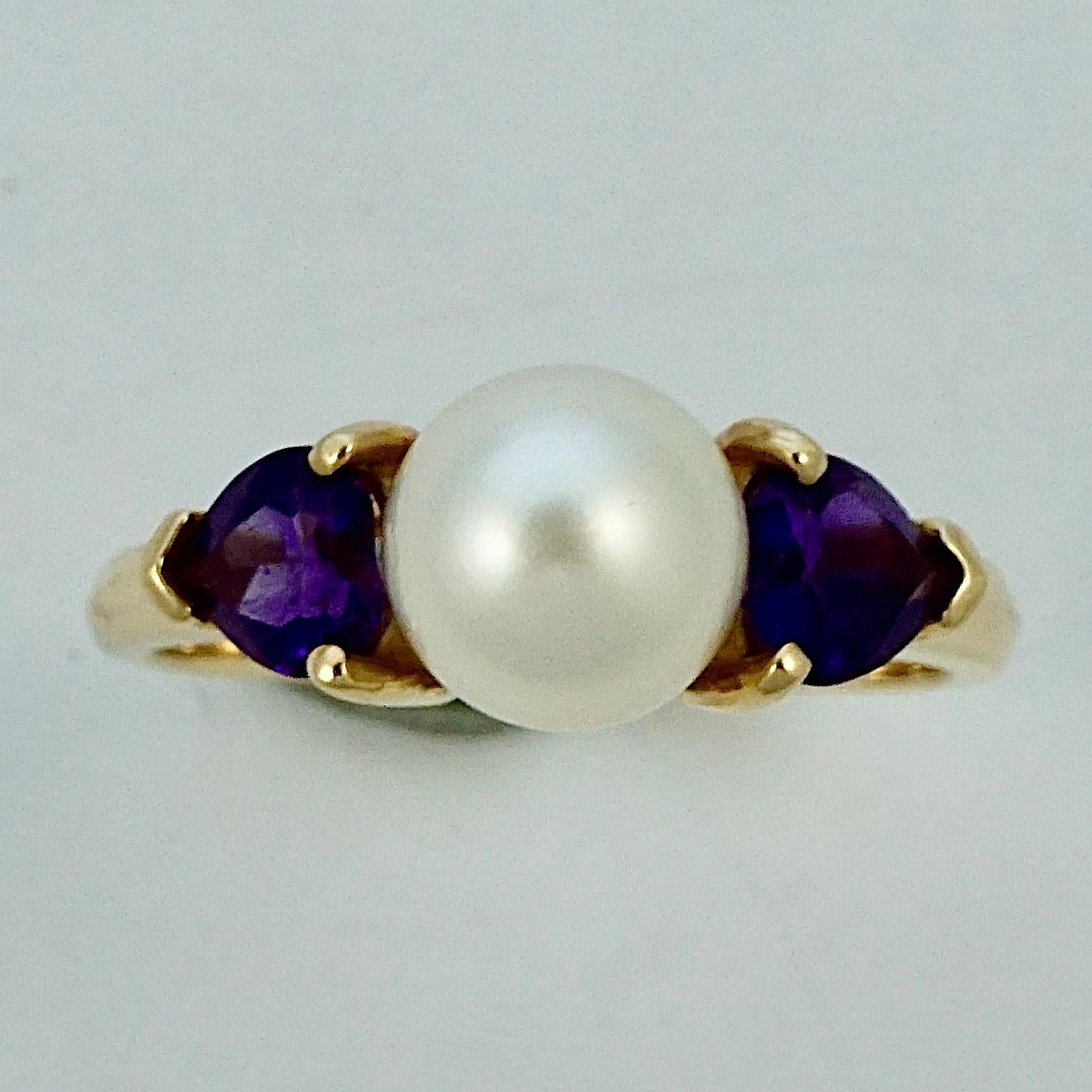 Bague en or 14K avec une belle perle de culture et deux améthystes en forme de cœur, dans une monture simple en relief. Bague de taille UK O / US 7, diamètre intérieur 1,8 cm / .7 inches. La perle mesure 7,5 mm et la profondeur de sertissage est de