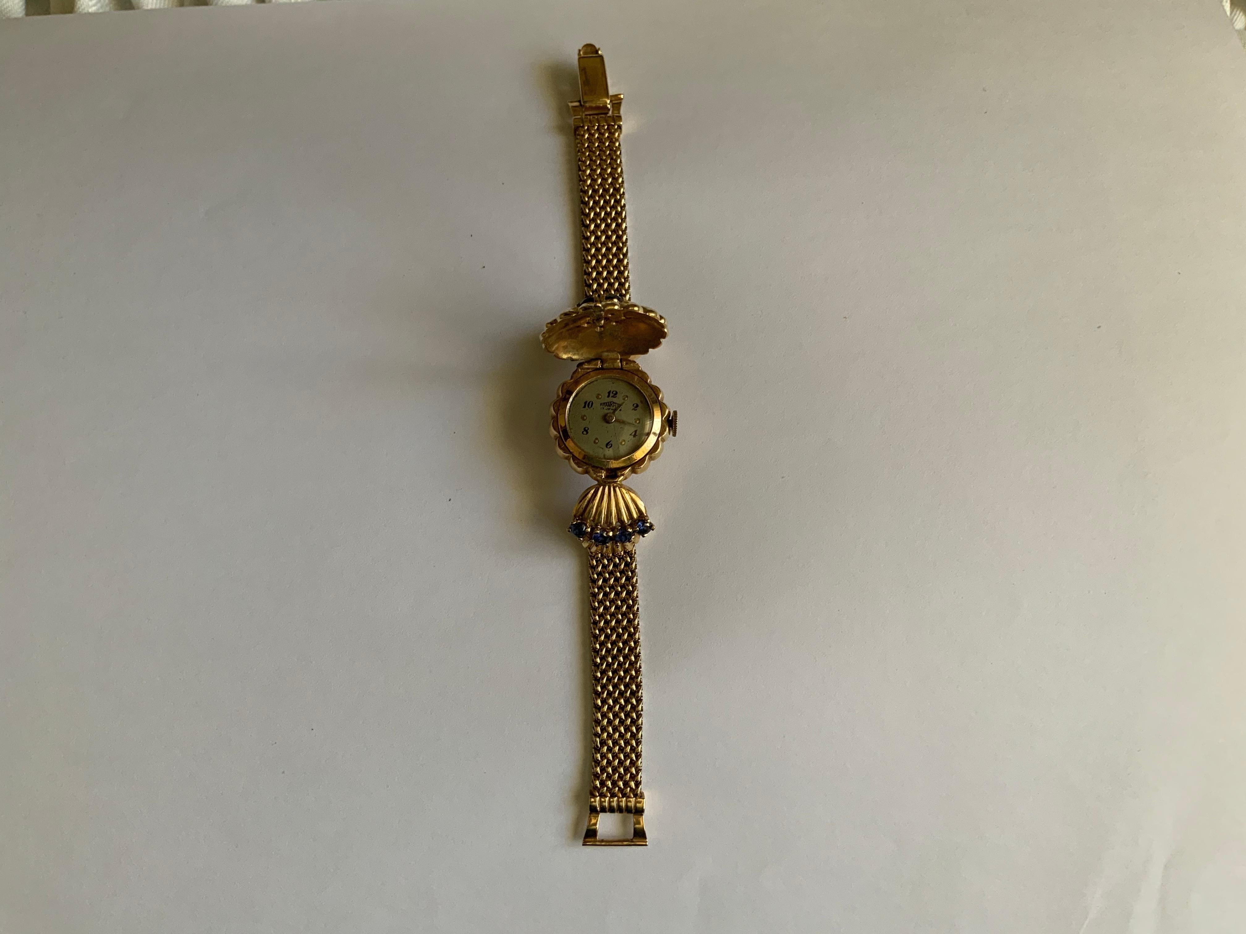 Dies ist ein 14K Gold, Diamanten und Saphiren Armband Uhr. Es zeigt eine versteckte runde Uhr (Frankfurter Handaufzugswerk mit 17 Steinen) mit einem goldenen Deckel in Form einer Blume mit geriffelten Blütenblättern, die in der Mitte mit fünf