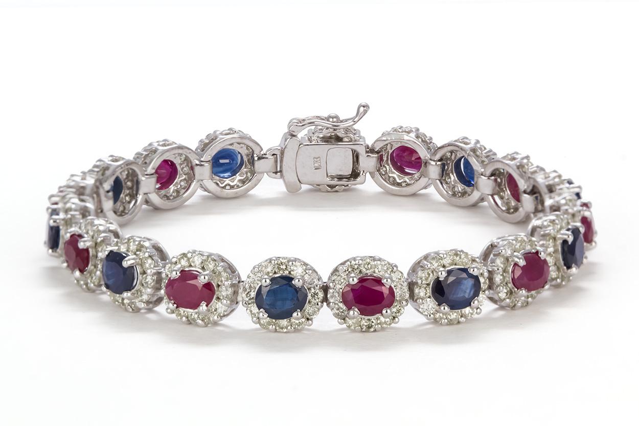 We are pleased to offer this 14k Gold Diamond, Ruby & Sapphire Bracelet. This beautiful piece is finely crafted from 14k white gold and features an estimated 7.00ctw oval cut blue sapphires, 6.00ctw oval cut rubies accented by 4.50ctw round