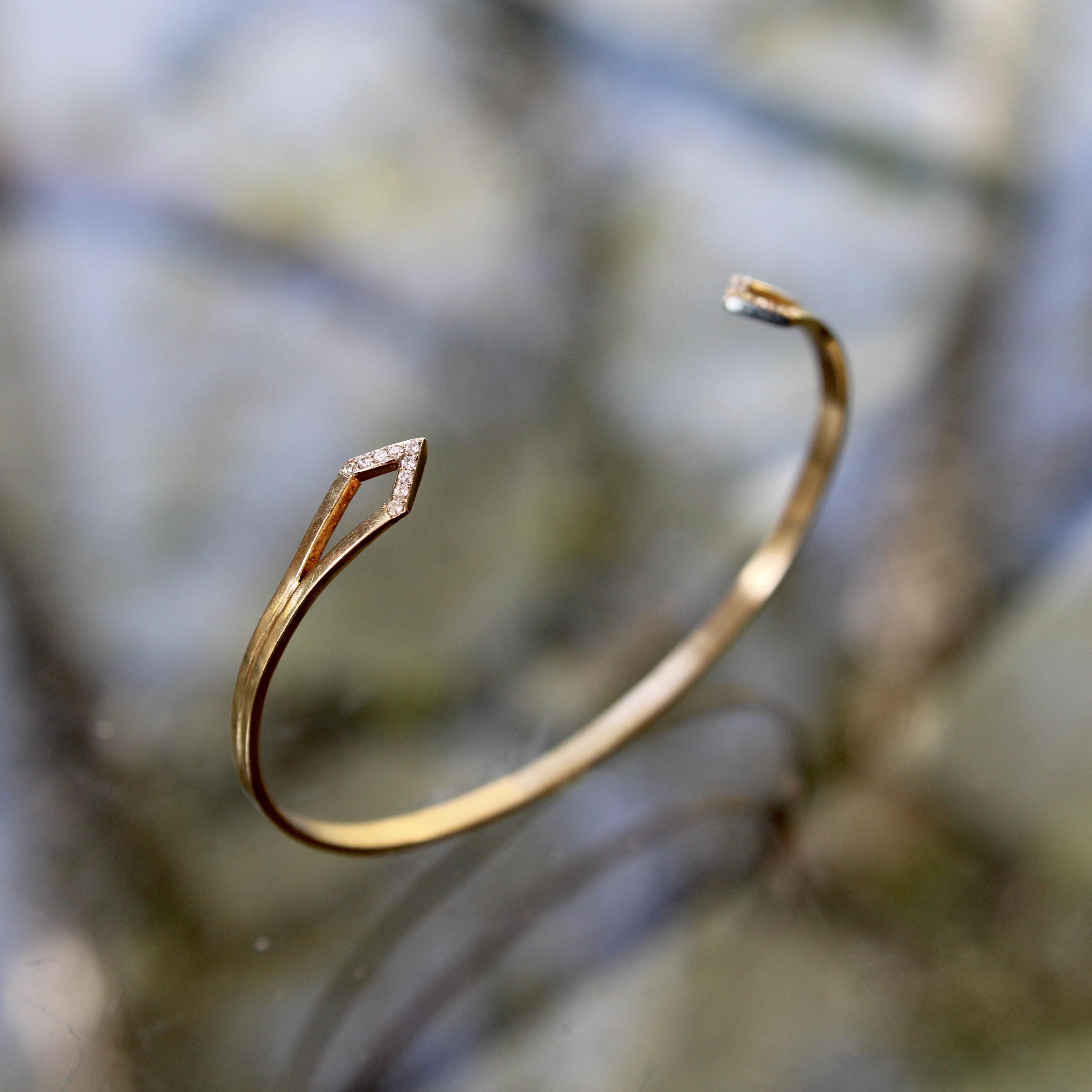 This simplistic and elegant cuff bracelet is made up of two bands that separate into triangular diamond encrusted tips, which feed back into the rest of the bracelet to create a sleek design. Each triangular tip contains nine 1 mm bead set diamonds