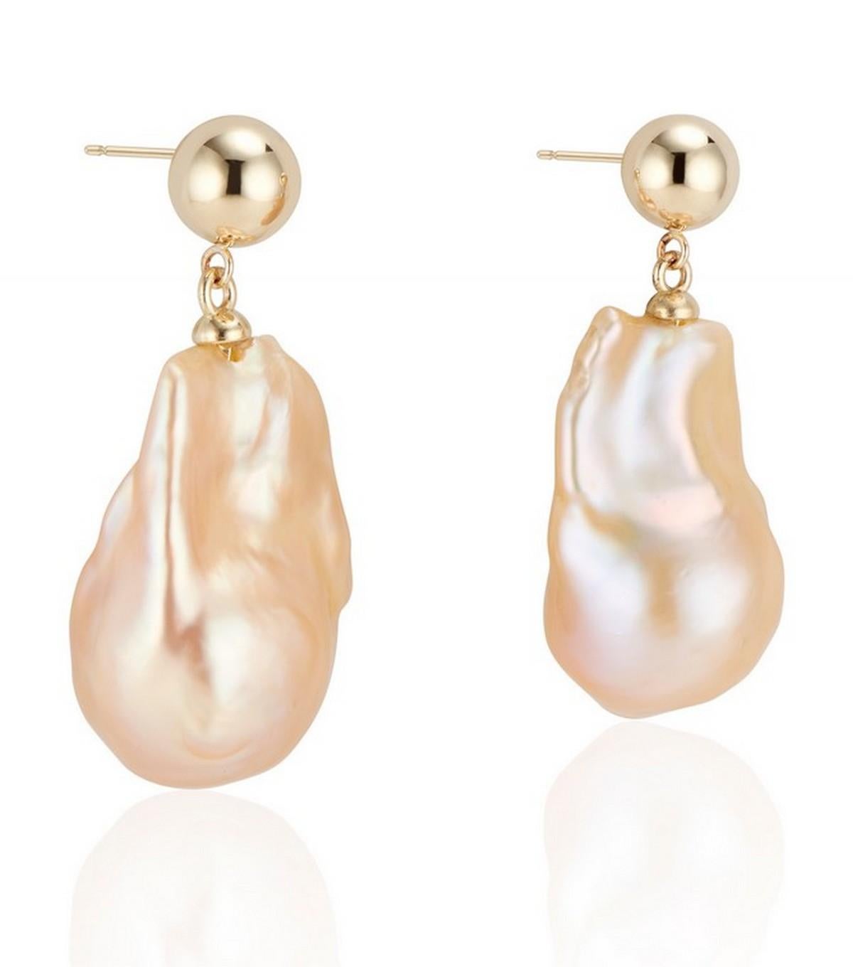 Flaunt your style with the Double Bubble earrings, showcasing a sleek 7.5mm hollow ball in 14k yellow gold, polished to a mirror shine, paired with a captivating golden-hued baroque pearl drop. The pearl's high-quality sheen casts a gentle, radiant