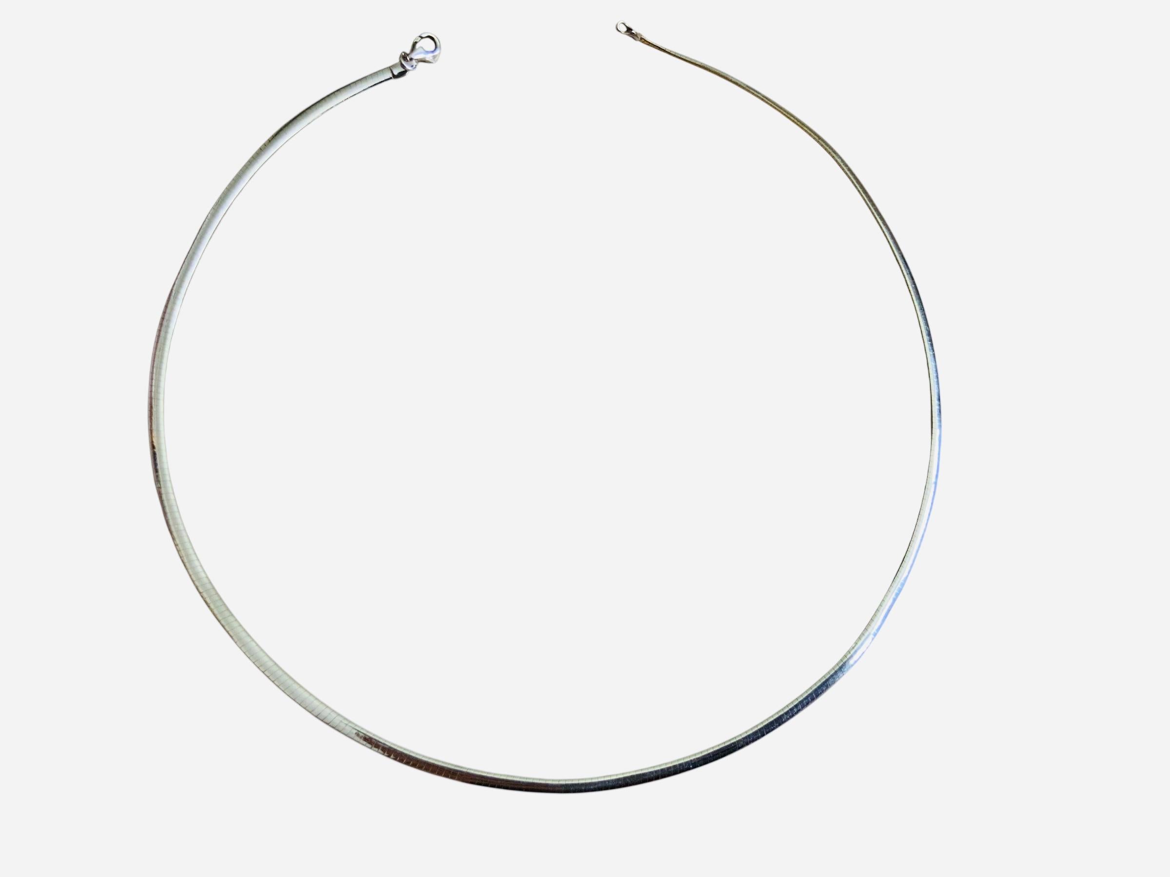 Se trata de un collar de eslabones Omega de oro de 14 quilates. Una cara es de oro amarillo y la otra de oro blanco. La longitud del collar es de 17 pulgadas. Tiene cierre de langosta. Su peso es de 9,6 gramos.