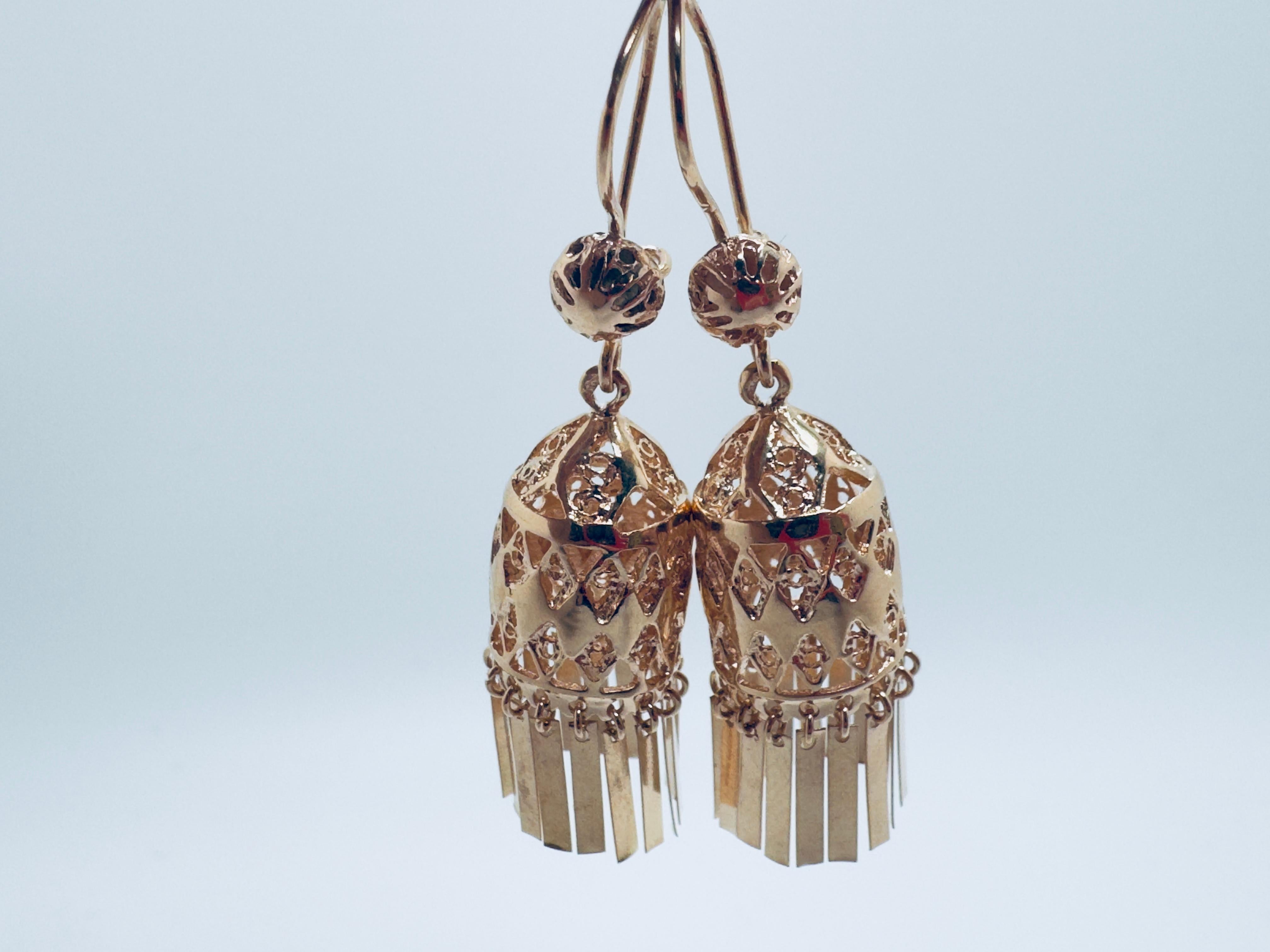 Estos impresionantes pendientes colgantes de oro de 14 quilates estilo Dubai presentan un diseño tradicional Jhumka de filigrana, que exhibe una artesanía intrincada y una elegancia cultural. Cada pendiente está cuidadosamente elaborado con