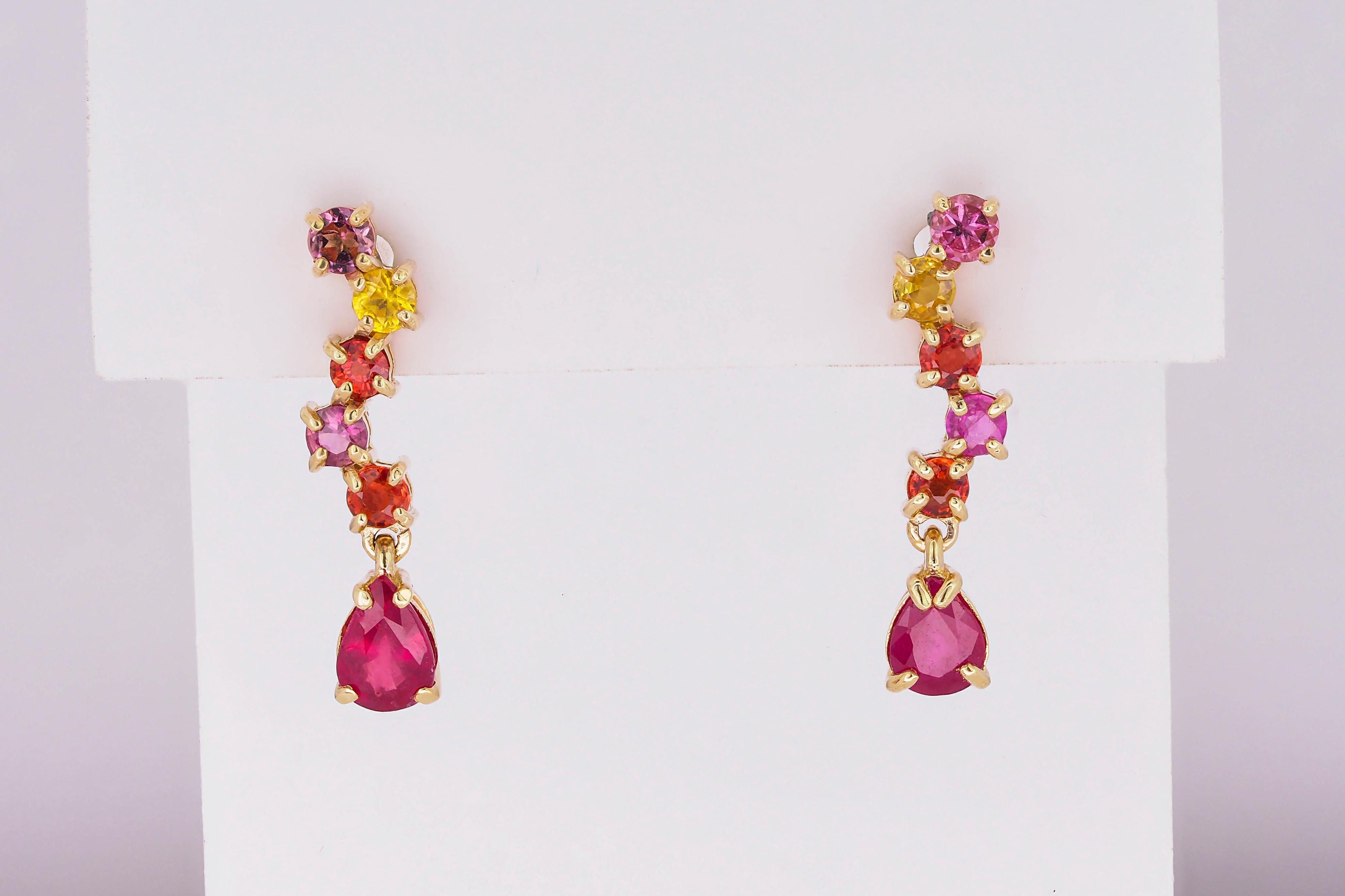 14kt solid gold earrings studs with multicolor natural sapphires and rubies. September birthstone. July birthstone.
Total weight: 2.30 g.
14kt yellow gold.
Size: 20 x 5 mm.

Central stones: Natural rubies - 2 pieces
Weight: approx 1.20 ct. total,