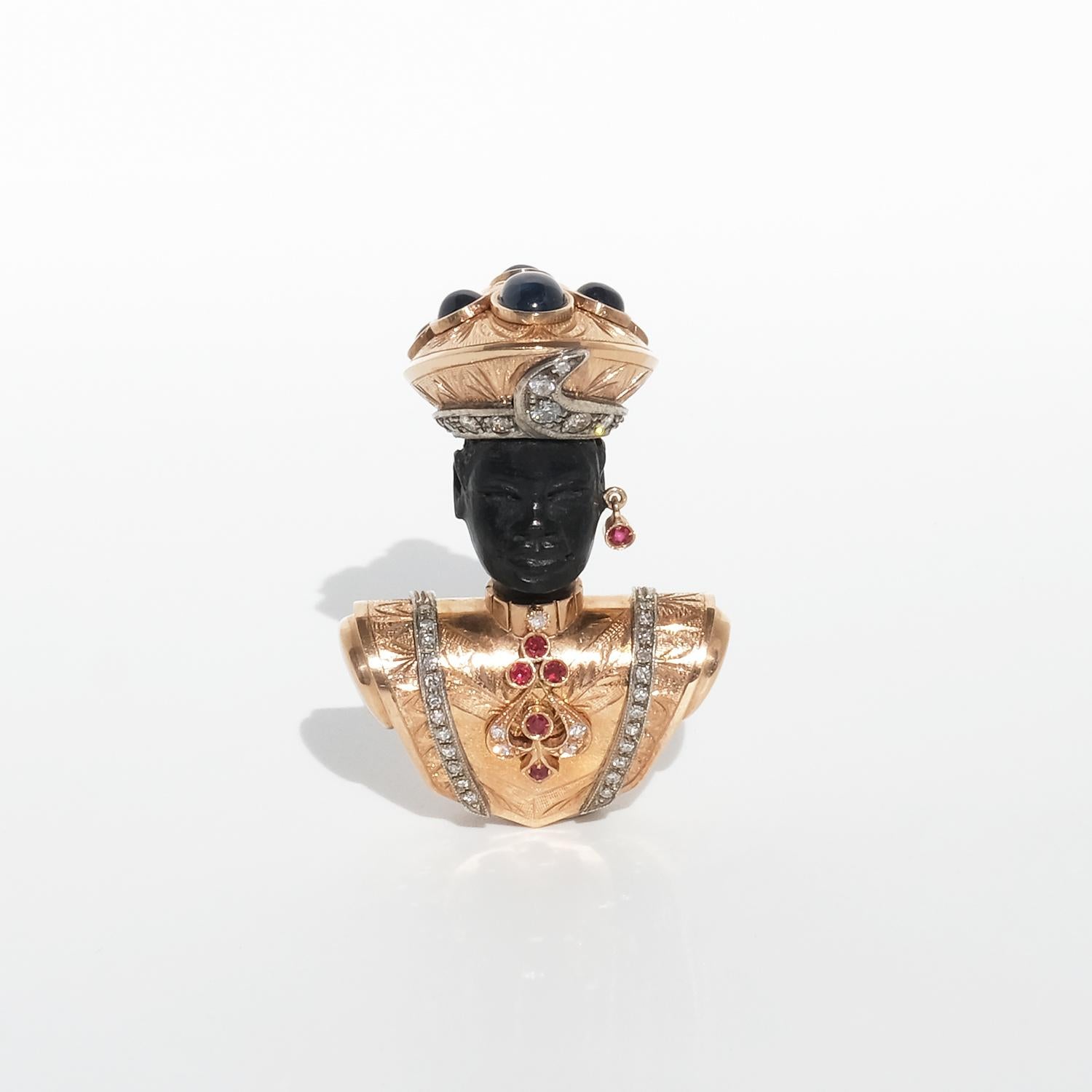 This exceptional brooch, crafted in 14-karat gold (with an 18-karat gold pin), portrays a regal figure with an ebony-carved face, exuding elegance and refinement. The turban is richly detailed, featuring an engraved, swirling pattern on top that