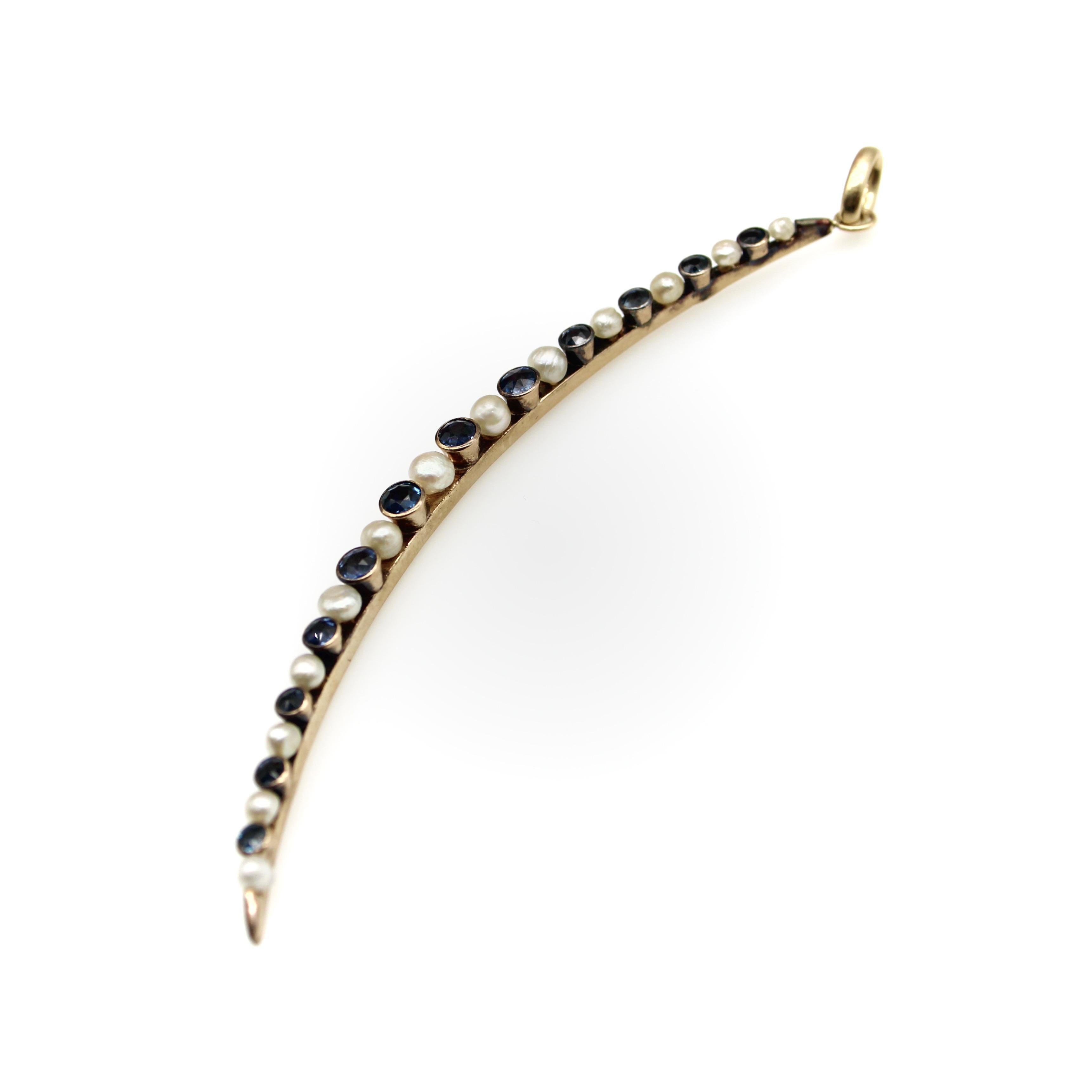 This elongated crescent moon contains graduated alternating pearls and sapphires. The pearls are half-drilled and attached with a post from the back, while the sapphires are bezel set into gold settings that appear cup-like when viewed from the