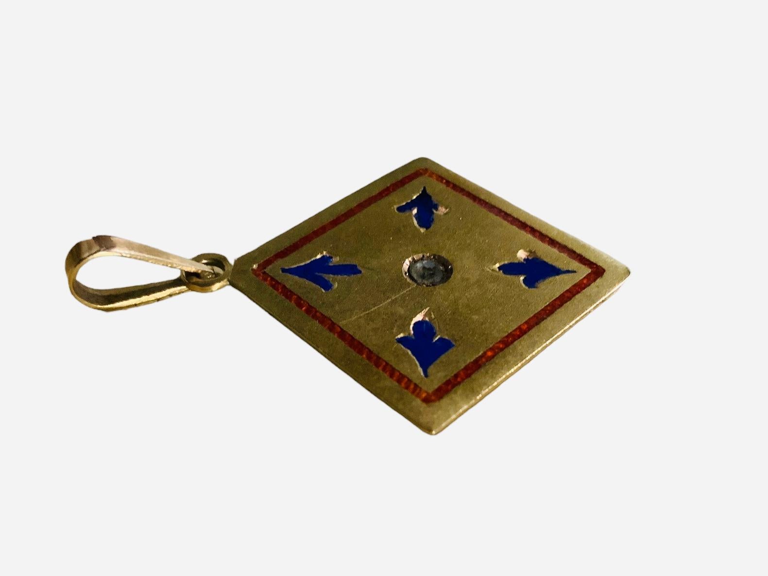 Dies ist ein 14K Gold-Emaille-Anhänger. Er zeigt einen quadratischen Anhänger, der in der Mitte mit einem runden geschliffenen Glas verziert ist. Von dort kommen vier königsblaue Emaille-Pfeile oder drei Blätter heraus, die in jede Ecke zeigen. Eine