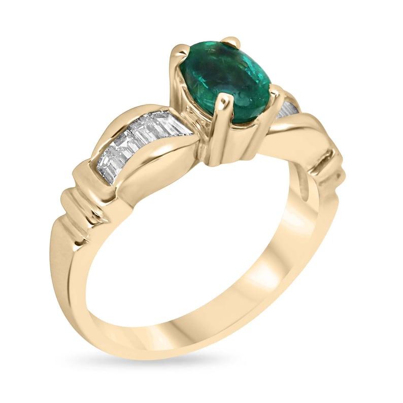 Rehaussez votre histoire d'amour avec cette bague de fiançailles enchanteresse ornée d'une émeraude ovale de 1,0 carat. Sa teinte vert foncé luxuriante et son éclat remarquable capturent l'essence de votre connexion profonde. Solidement maintenu