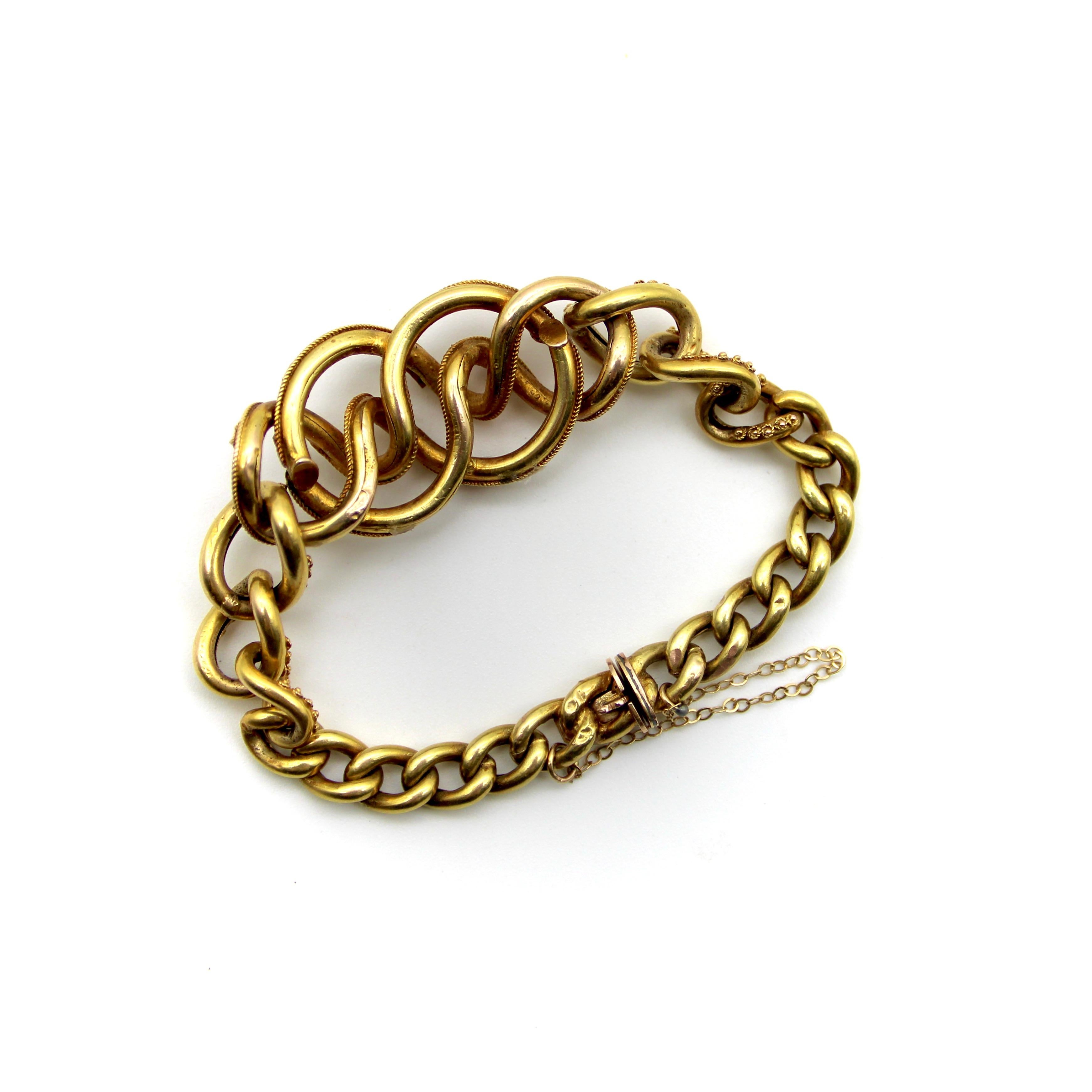 Circa 1880’s, this 14k gold Etruscan Revival bracelet has a lover’s knot motif adorned with pearls and garnets. The central part of the bracelet consists of matching graduating curb links that extend from the main section into smaller, tighter curb