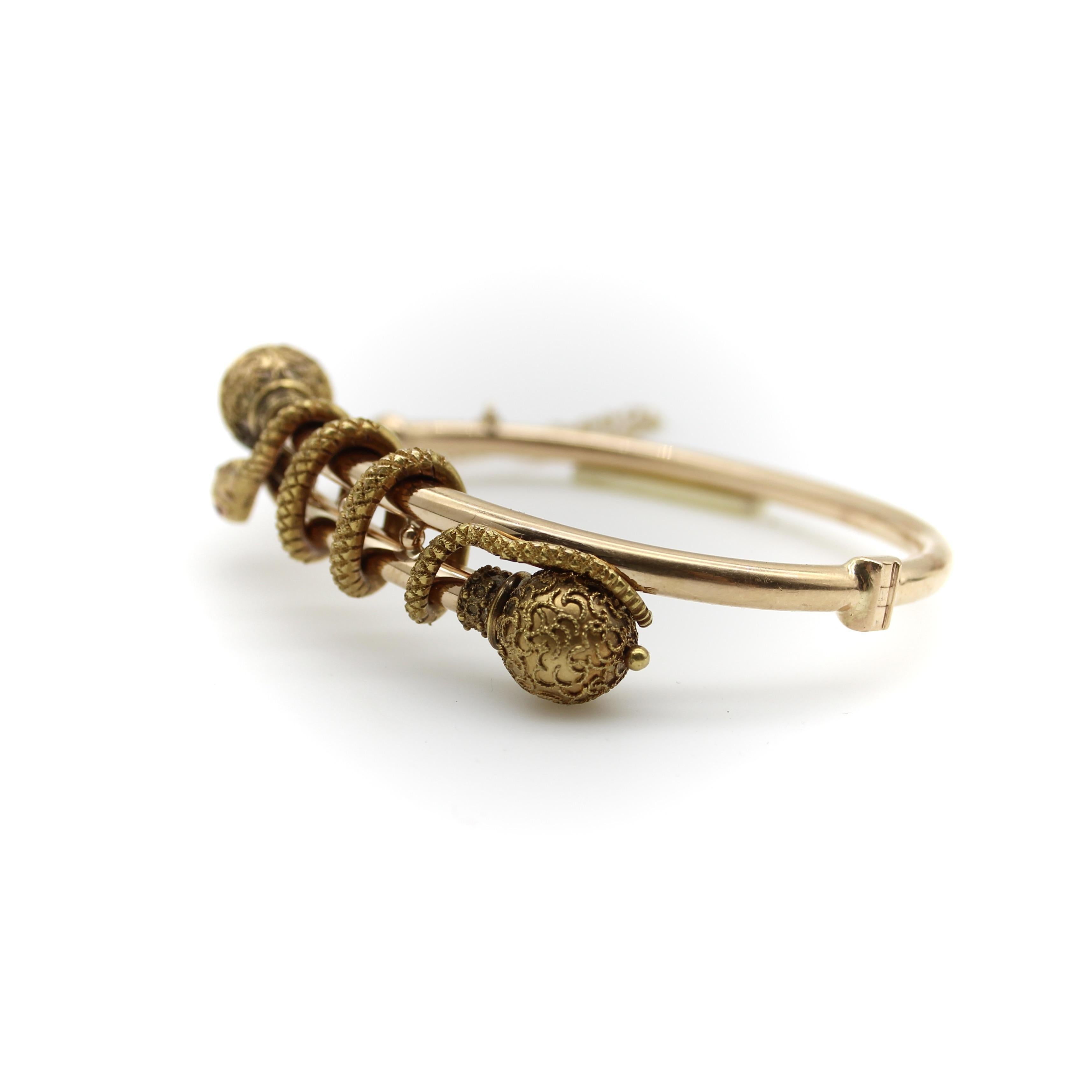 This classic 14k gold Etruscan Revival bypass bracelet features a snake that intertwines itself along the bracelet, as if it were holding the piece together. The bracelet’s bypass consists of two ball terminals adorned with intricate twisted