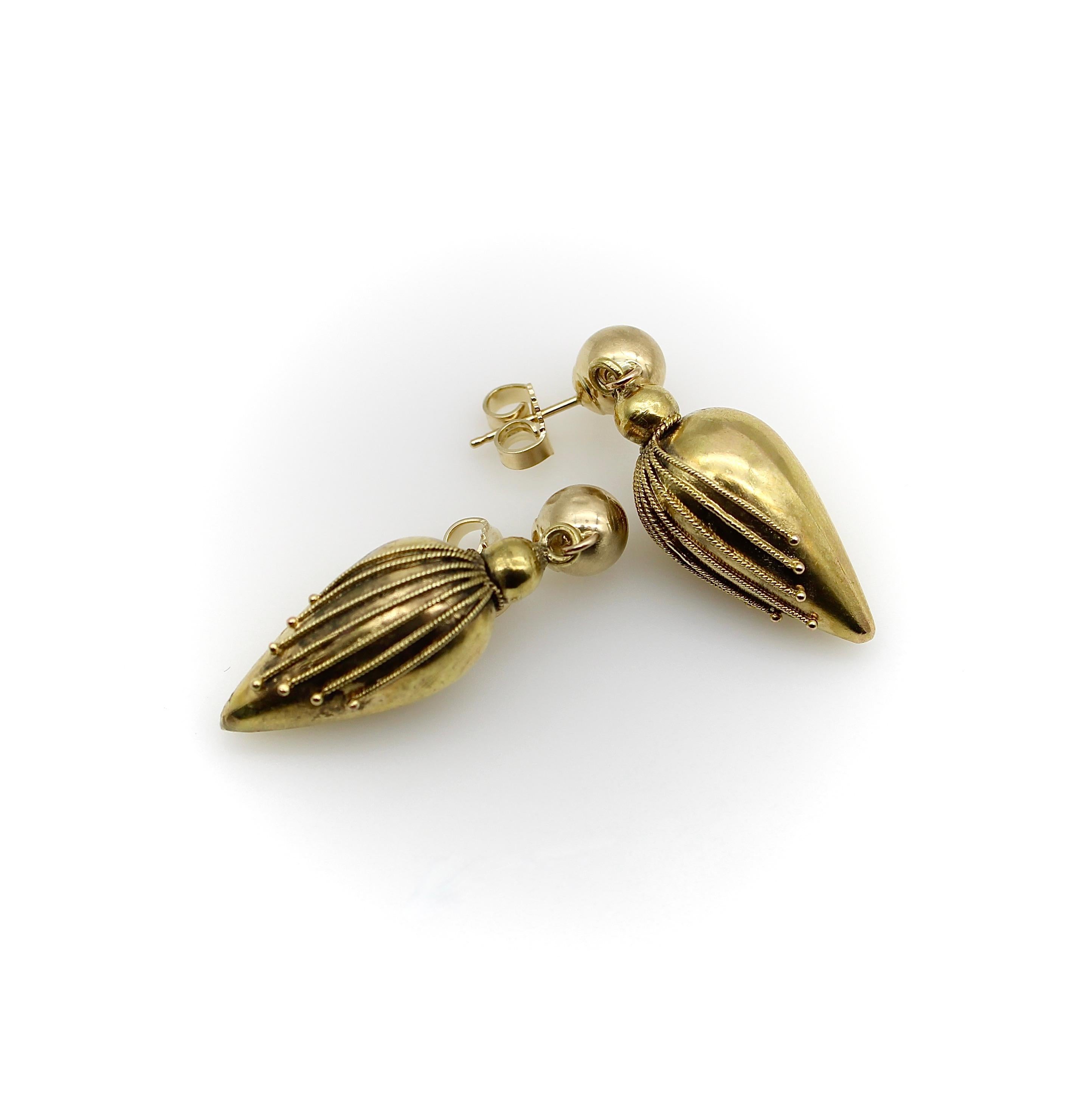 Beautiful torpedo-shaped drops are suspended from classic balls in this wonderful pair of Etruscan Revival 14k gold earrings. The fronts of the torpedos are decorated with twisted wires of varying lengths that create a chevron pattern. Each of the