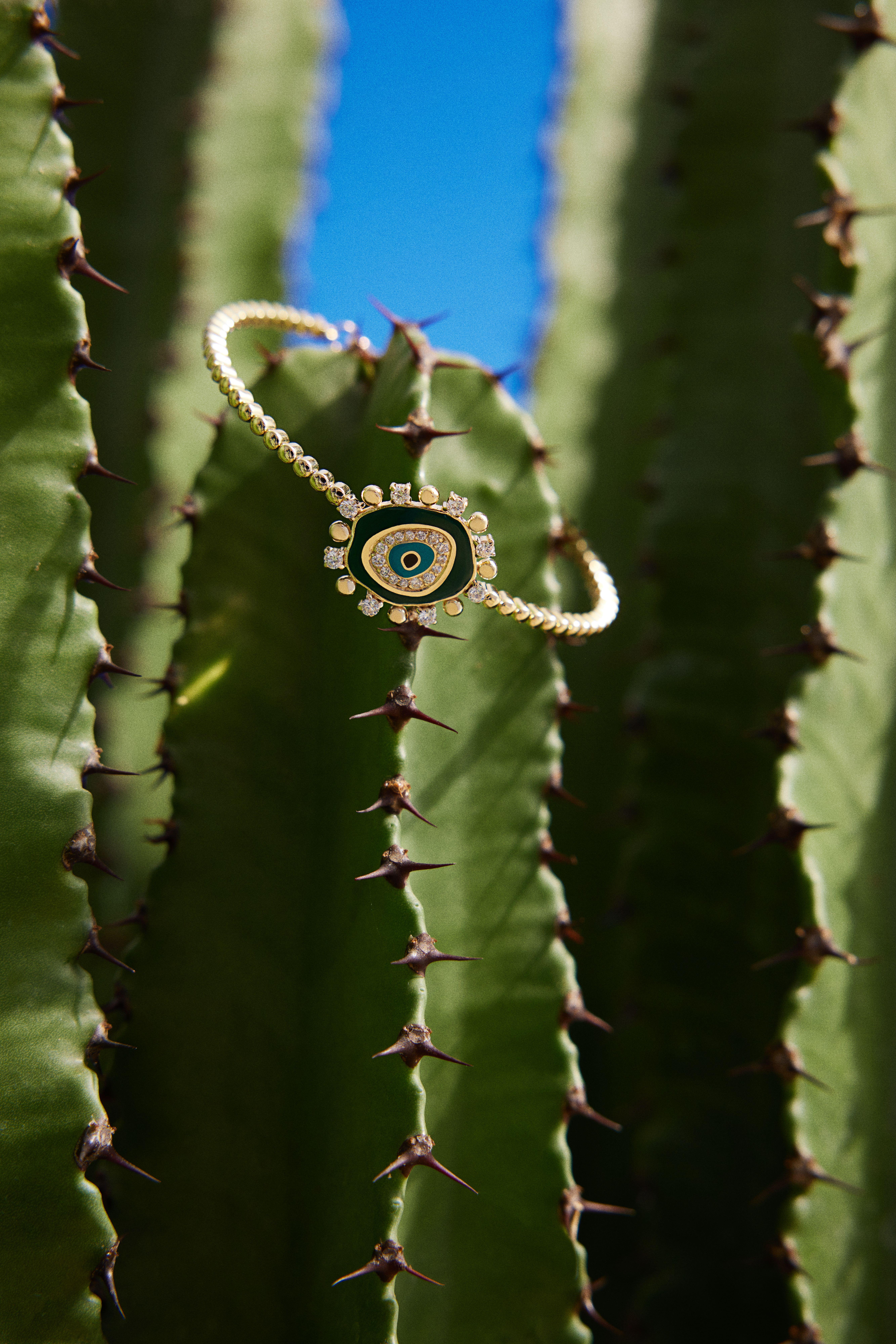 14k Gold Nazar bangle with a unique shape. Created with Enamel & Diamonds.