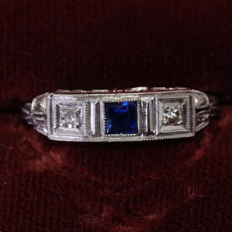 One-ladies Platinum ring with central square cut sapphire surrounded by 2 round brilliant cut diamonds. Each shoulder is channel set with tapered baguette-cut diamonds. Estimated brilliant weight of 0.2 ct. Ring size 5.5