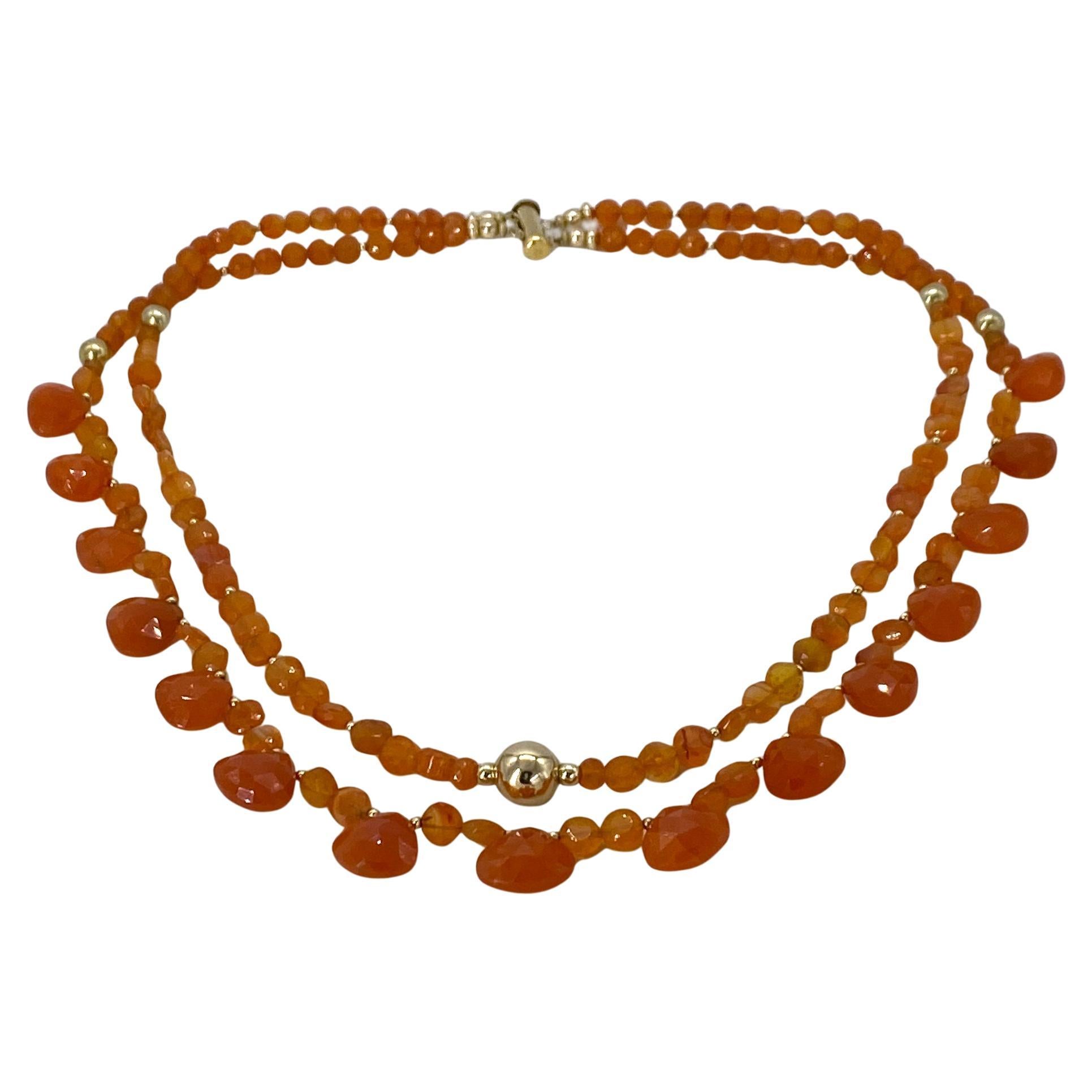 Nous avons créé ce collier de pierres de cornaline de couleur orange et des pendentifs en forme de cœur briolette. Des perles de cornaline rondes et facettées de 6 mm et de 5 mm, ainsi que des boucles d'oreilles en or 14K complètent ce