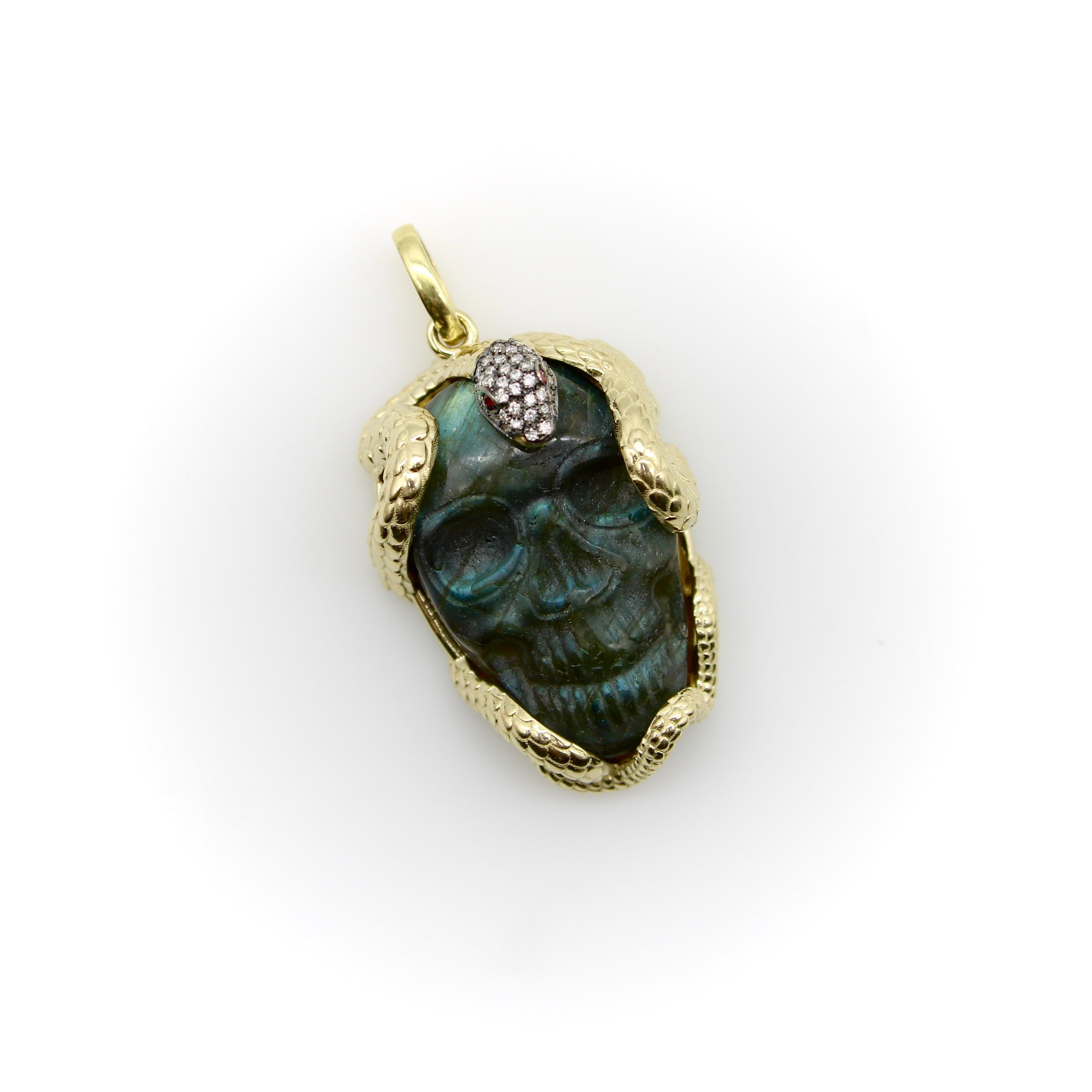 In 14k gold, an intertwining, well-articulated snake curves and clings its way around a carved labradorite skull. The top of the snake’s head is embedded with micro pave diamonds and an antique finish, offset with two ruby eyes. The snake’s detail