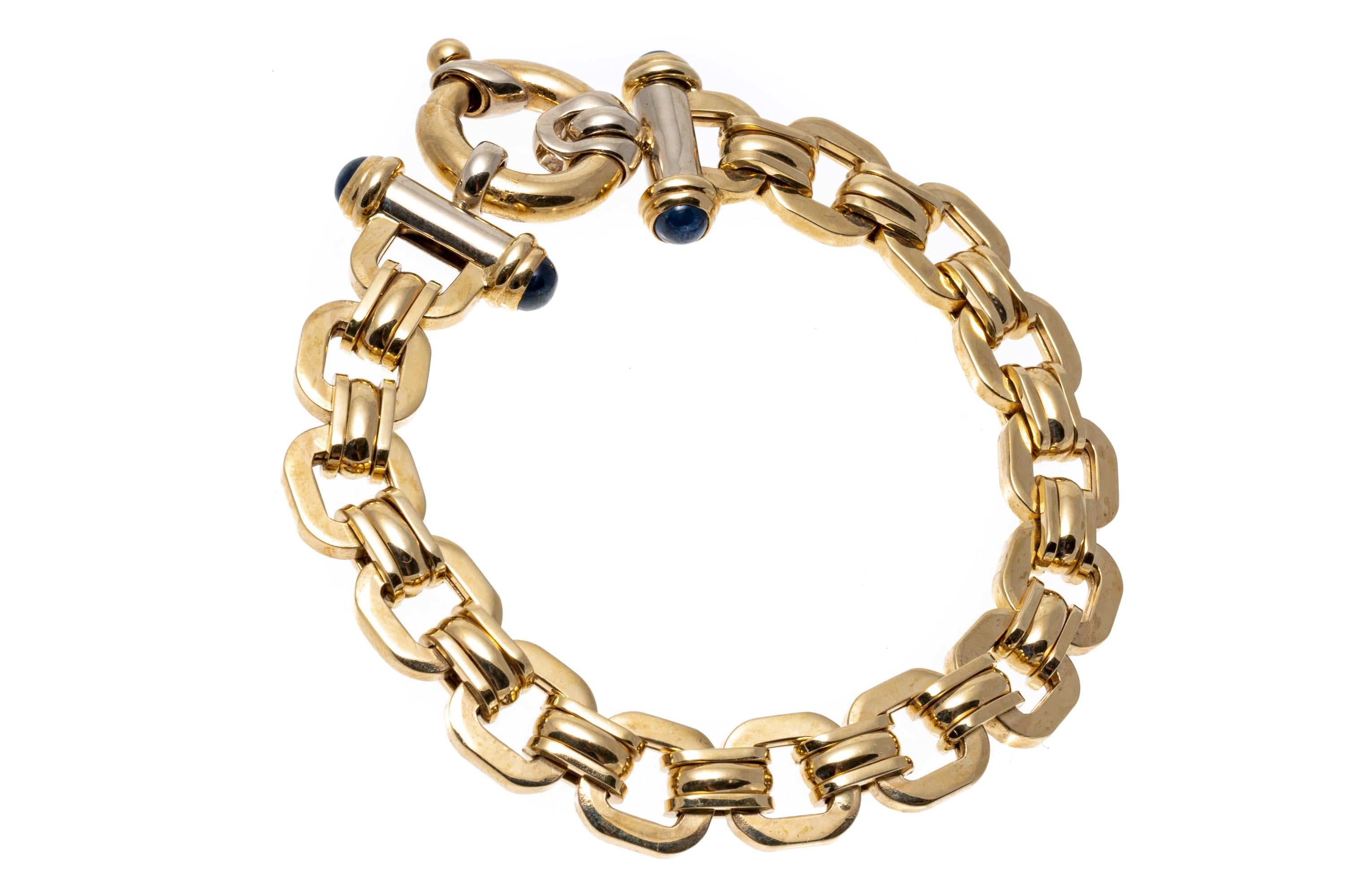 An Italian design with a contemporary feel, this 14K yellow gold bracelet has rounded square links alternating with ribbed connecting links. Set at either end of the chain and accenting the clasp are round cabochon cut sapphires with a deep navy