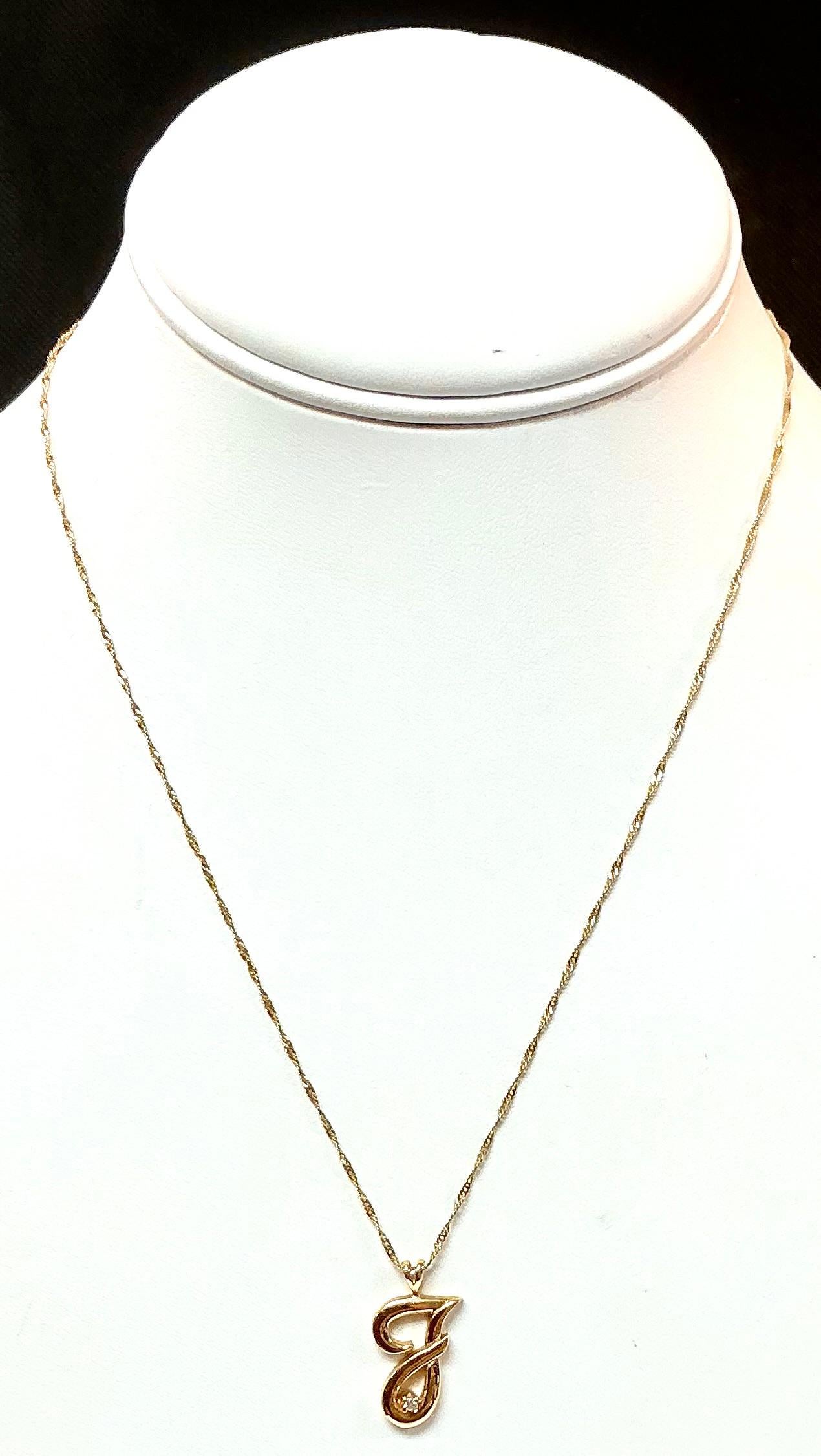 Collier à pendentif initial en or jaune 14K. Le collier comporte un gracieux pendentif en forme de 