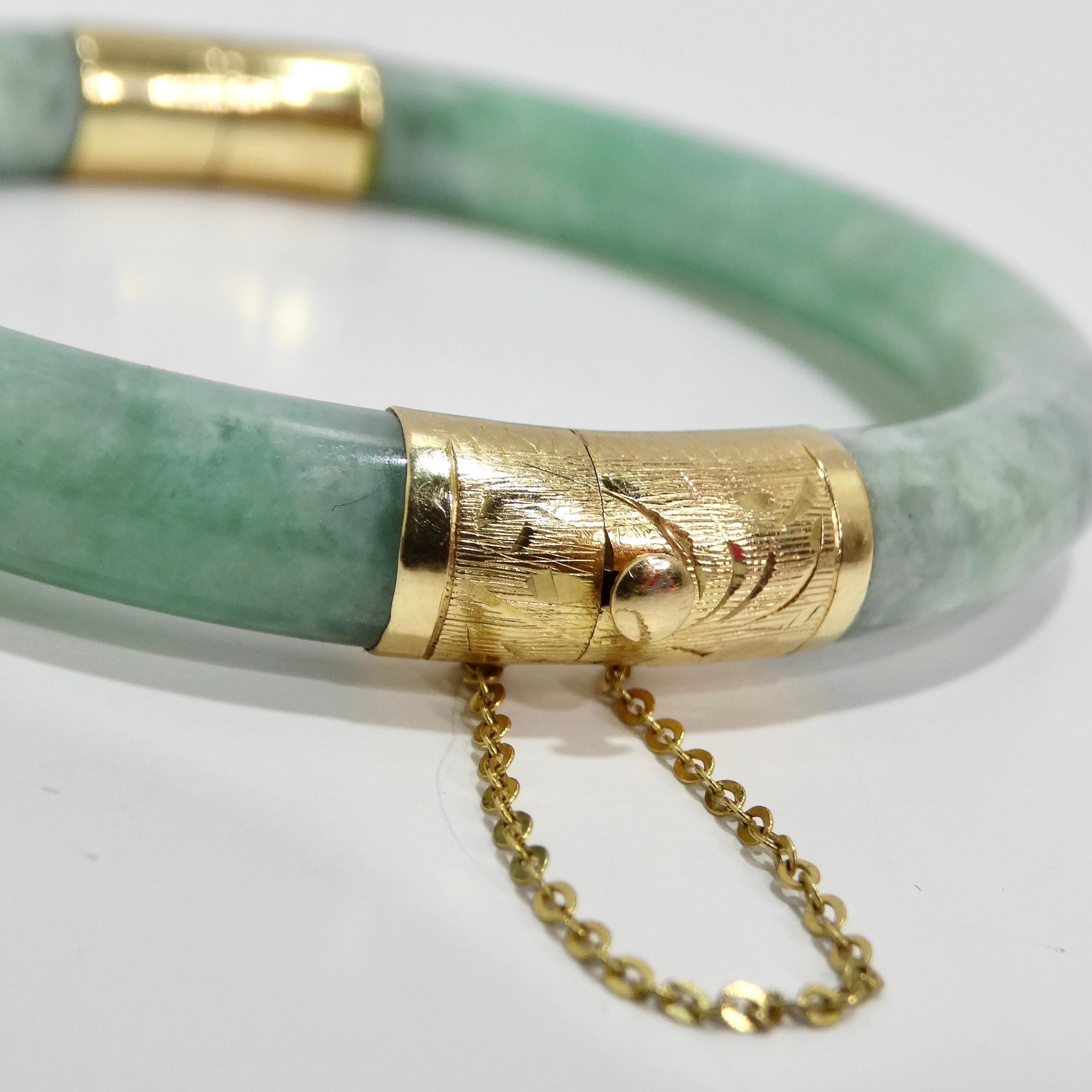 Indulge in timeless elegance with the 14K Gold Jade Jadeite Hinged Bangle Bracelet, a stunning piece that seamlessly blends precious materials with intricate craftsmanship. This estate jadeite bangle features a captivating natural light green