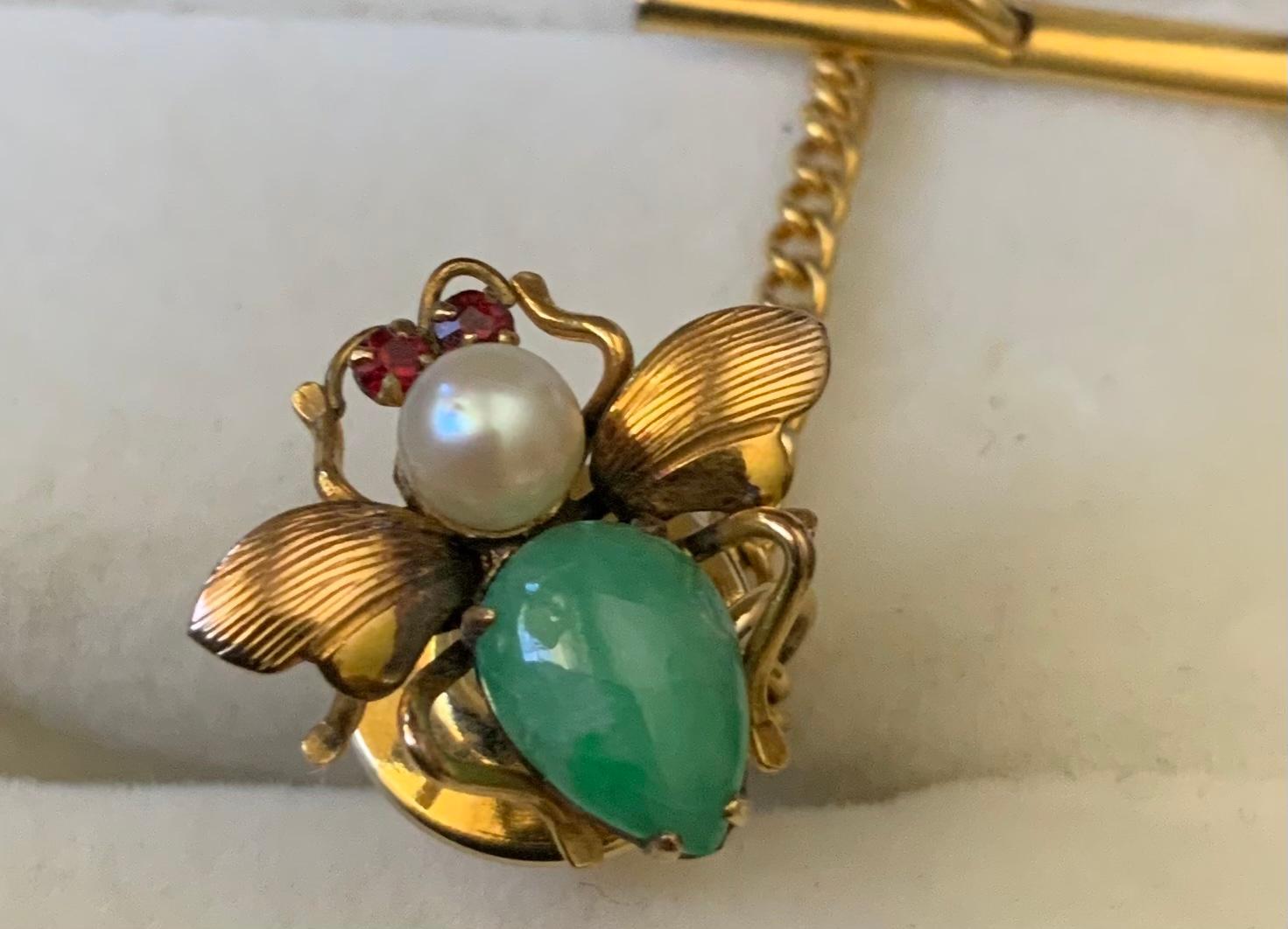 Il s'agit d'une épingle à cravate en or jaune 14K représentant un insecte. Il représente un jade vert mesurant 8,3 mm x 5,8 mm (corps), une perle de culture d'Akoya de 4,5 mm (tête) et deux grenats (yeux) montés sur une épingle à mouche des fruits
