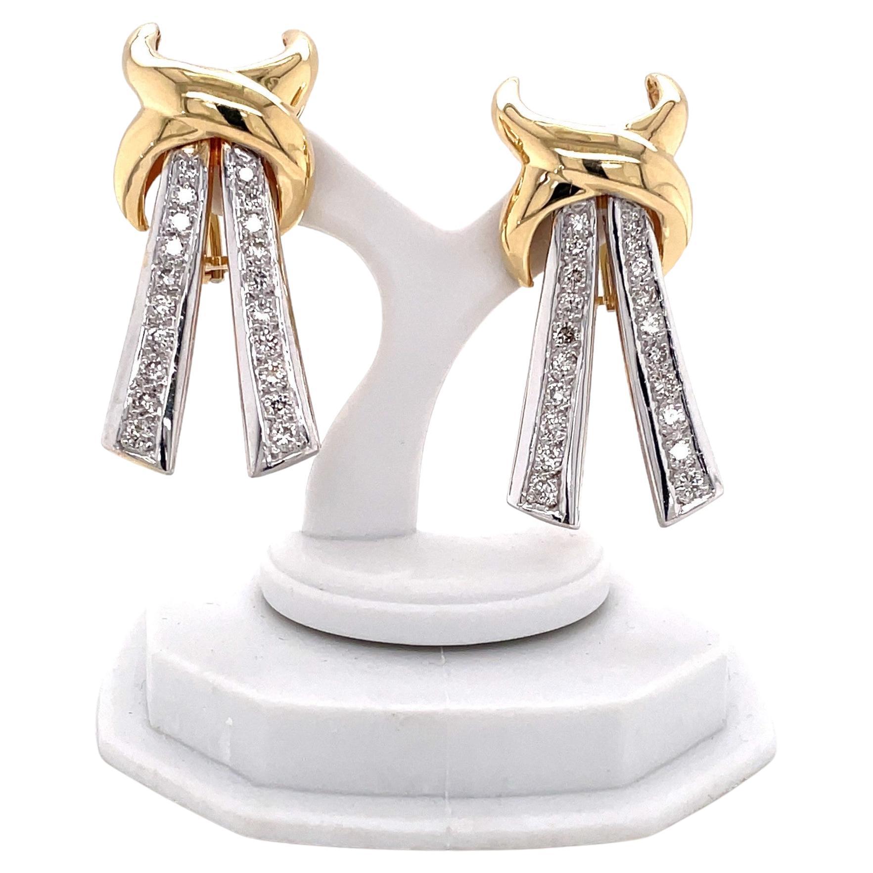 A twist of fourteen karat yellow gold hosts the dramatic diamond covered ribbon drop of this bow tie inspired pair of elegant earrings. Quality Italian made with twenty round faceted H/VS diamonds accents, 1.12 carats total weight. For pieced ears,