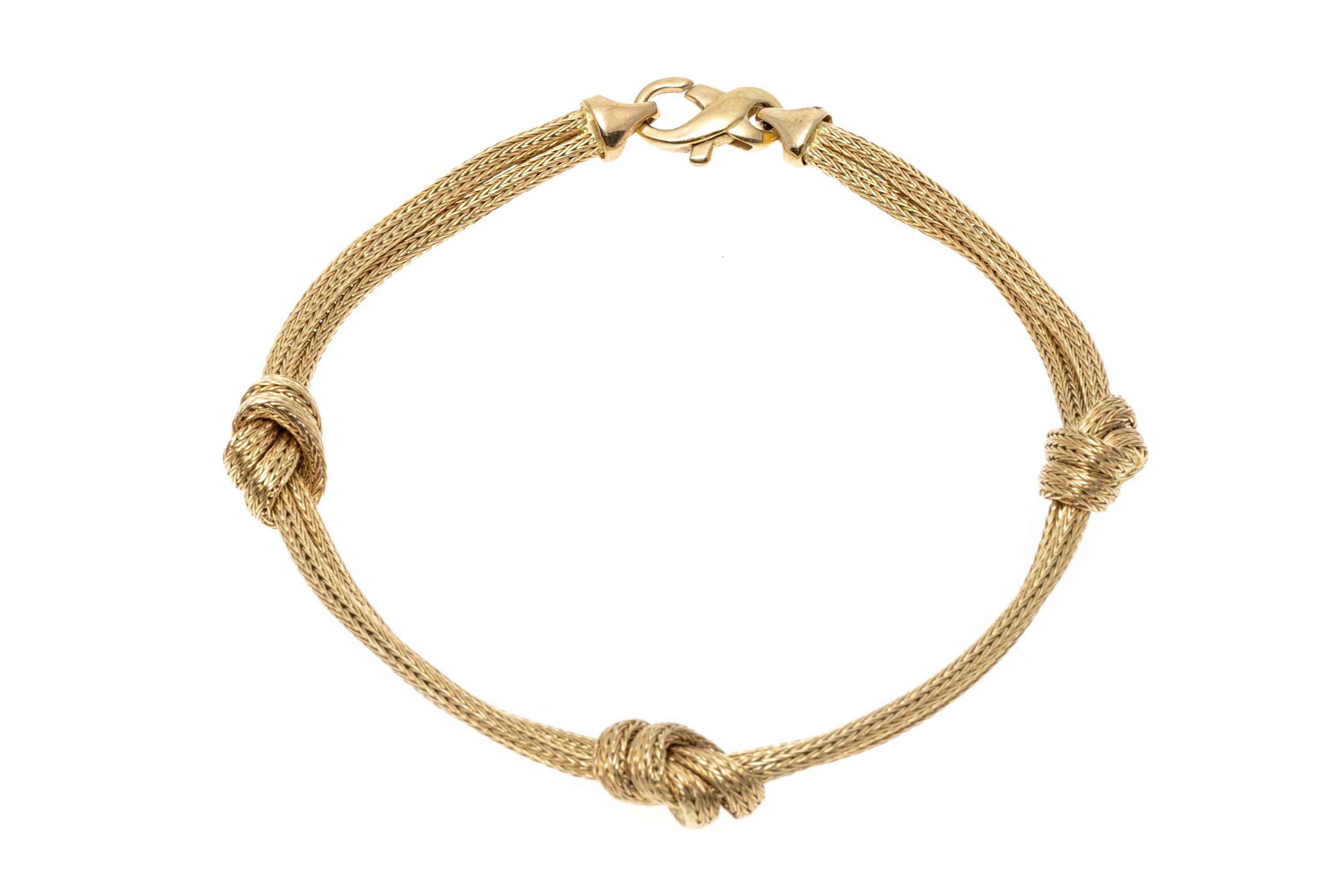 This graceful little bracelet is crafted of 14K yellow gold with two foxtail style chains. Set at intervals along the bracelet are three overhand knots. Lobster claw style clasp. 
Marks: 585 Italy
Dimensions: 7 1/4
