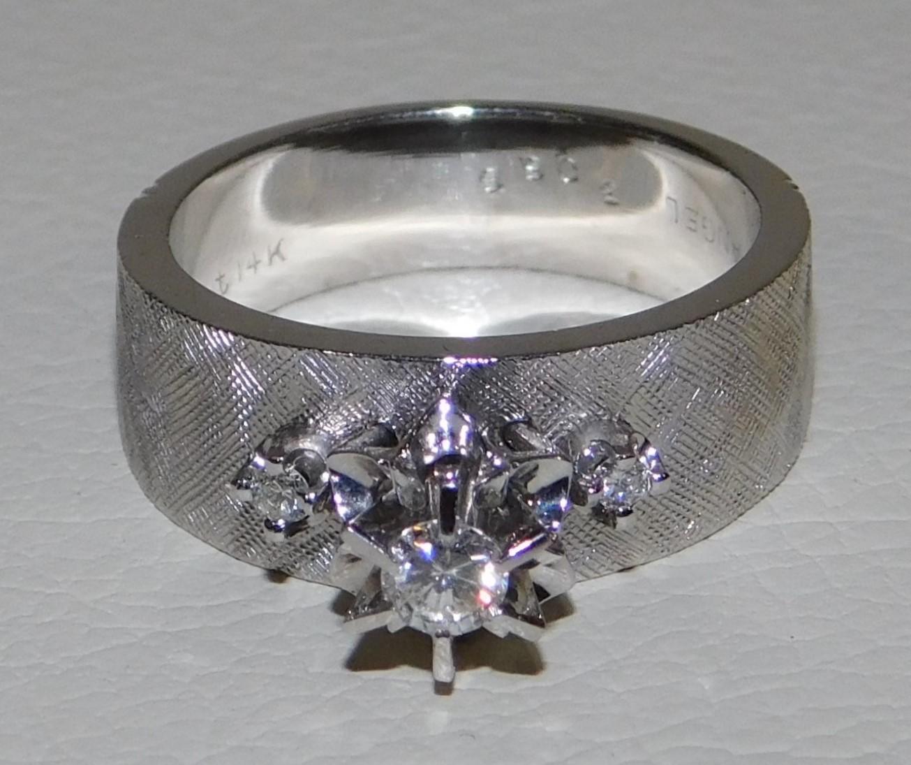 Lady's stamped 14-karat gold diamond ring with a bright polish and textured finish in very good condition. Three stone design, main stone is a raised with star like detail around. One diamond set on each shoulder. Shank measures approximately 7.15mm